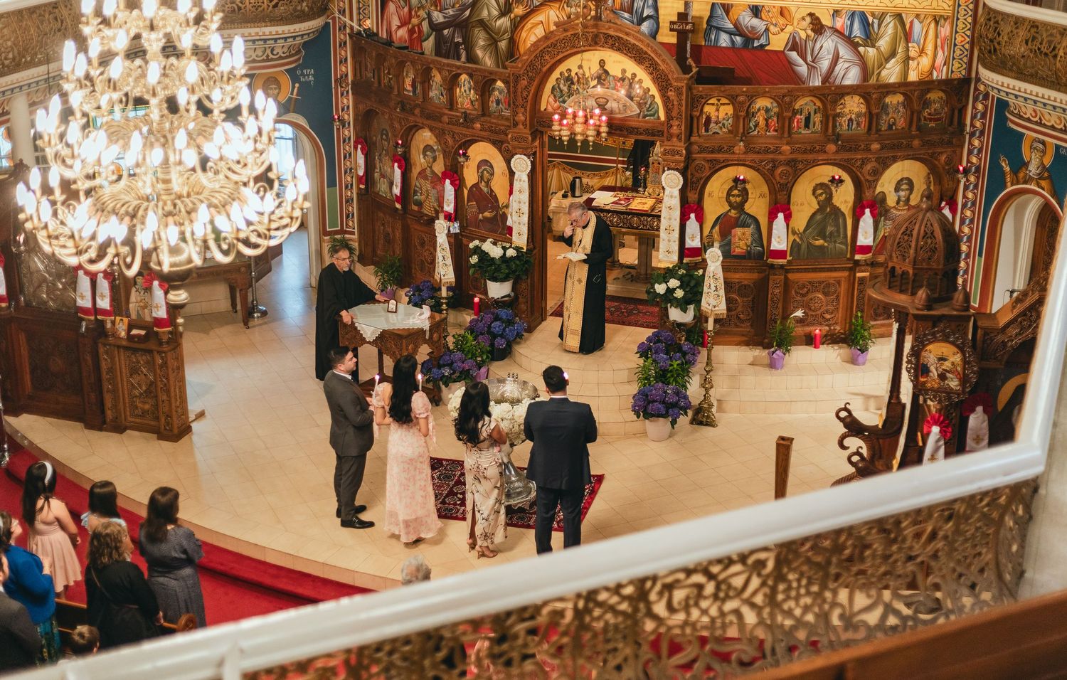 Ornate church interior with chandeliers and religious icons during a ceremony.