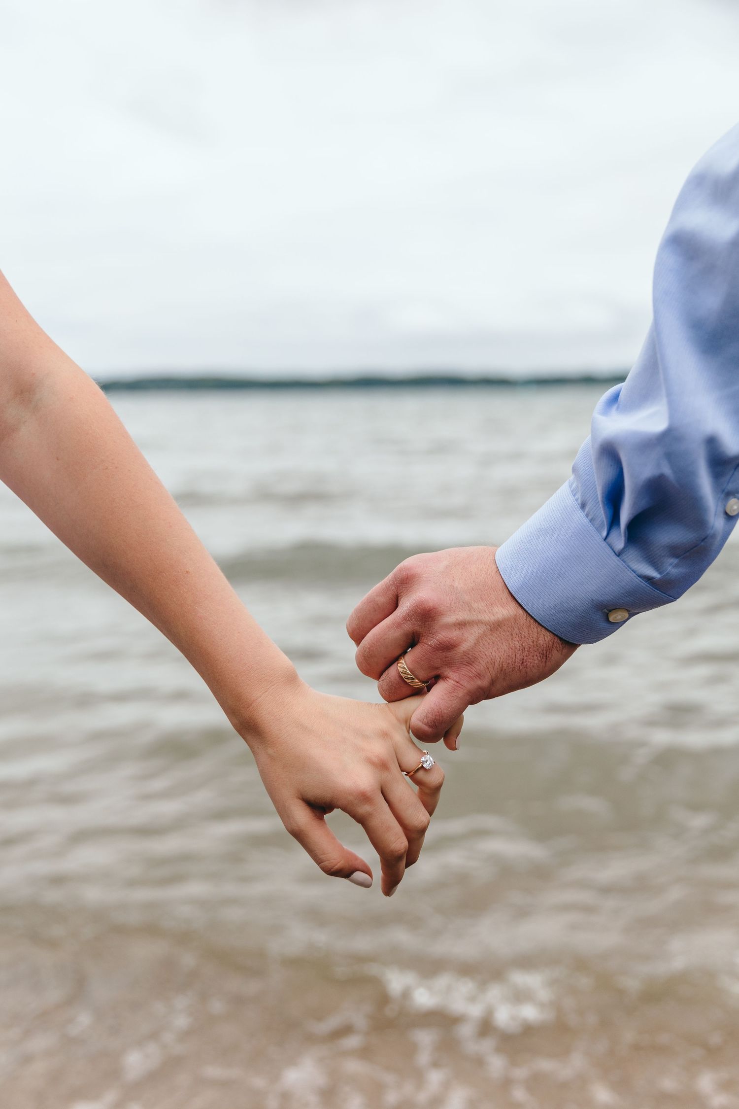 Close-up shots of two hands holding each other against a waterfront background.