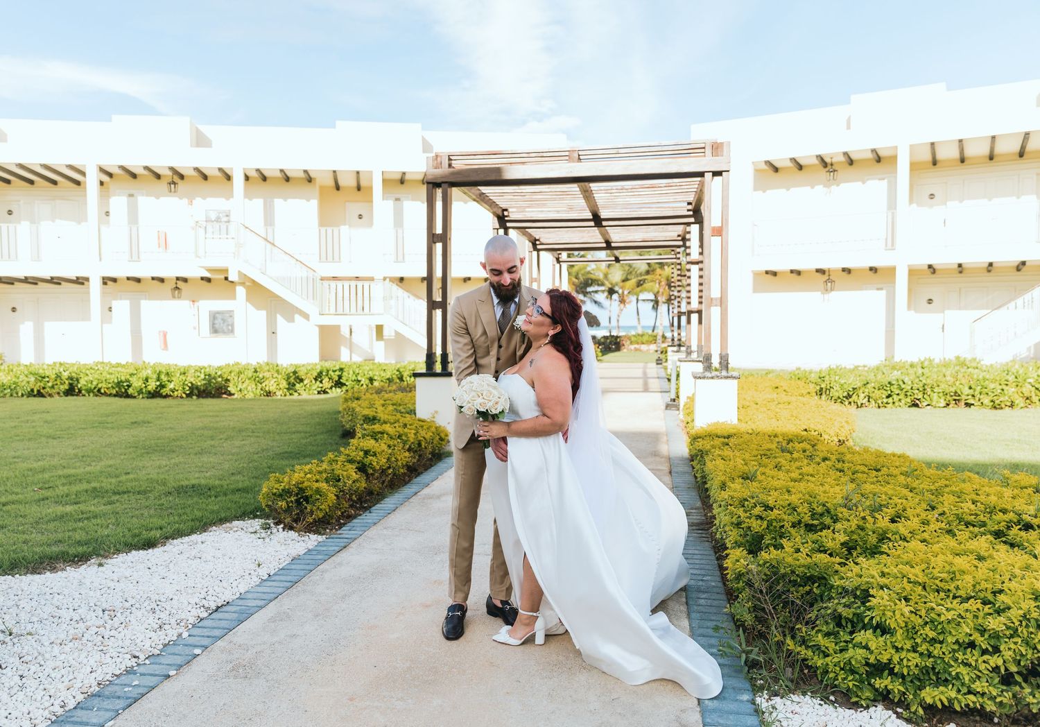 A joyful wedding couple sharing a playful moment in an outdoor walkway.