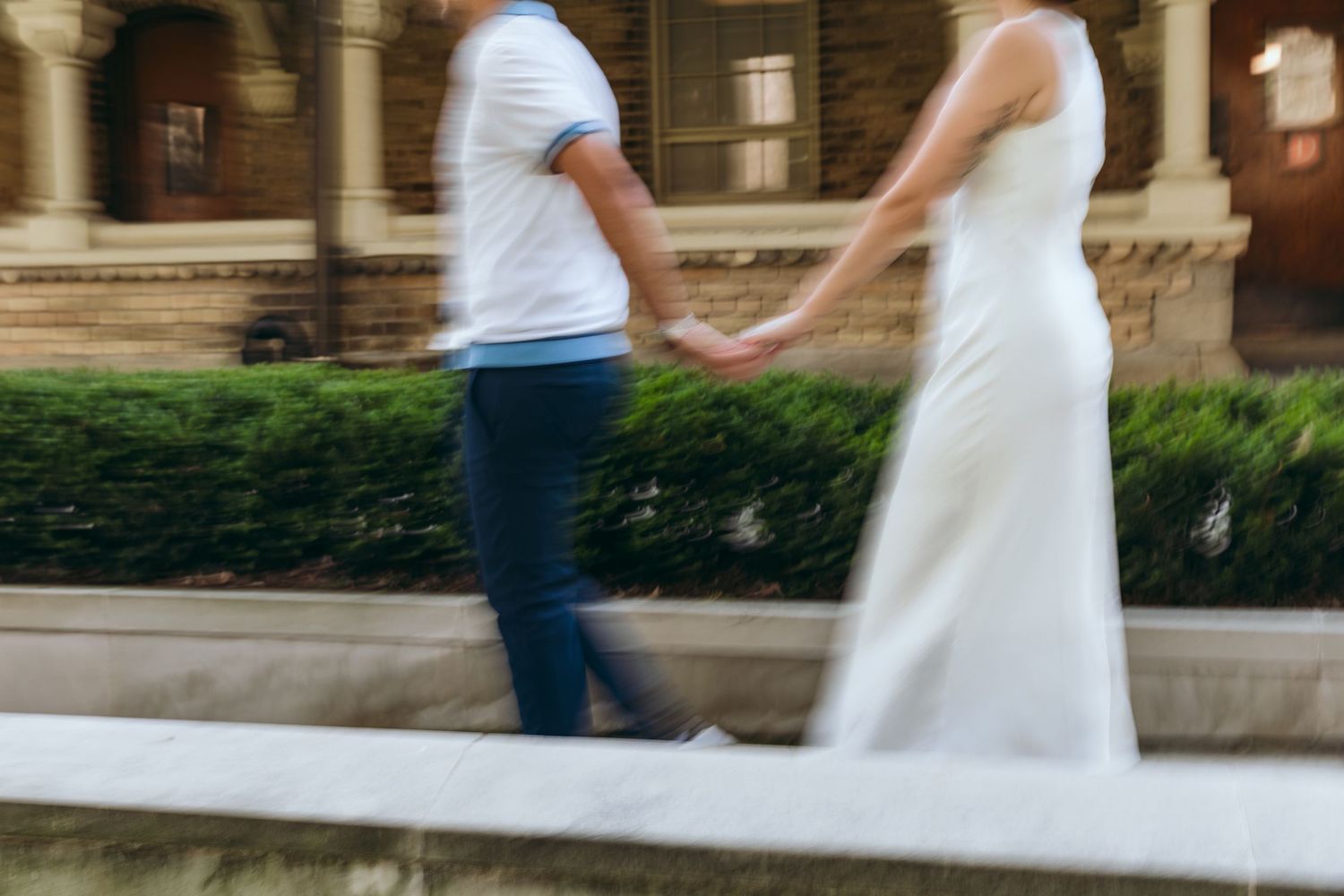 A motion-blurred couple walking together near Gothic architecture.