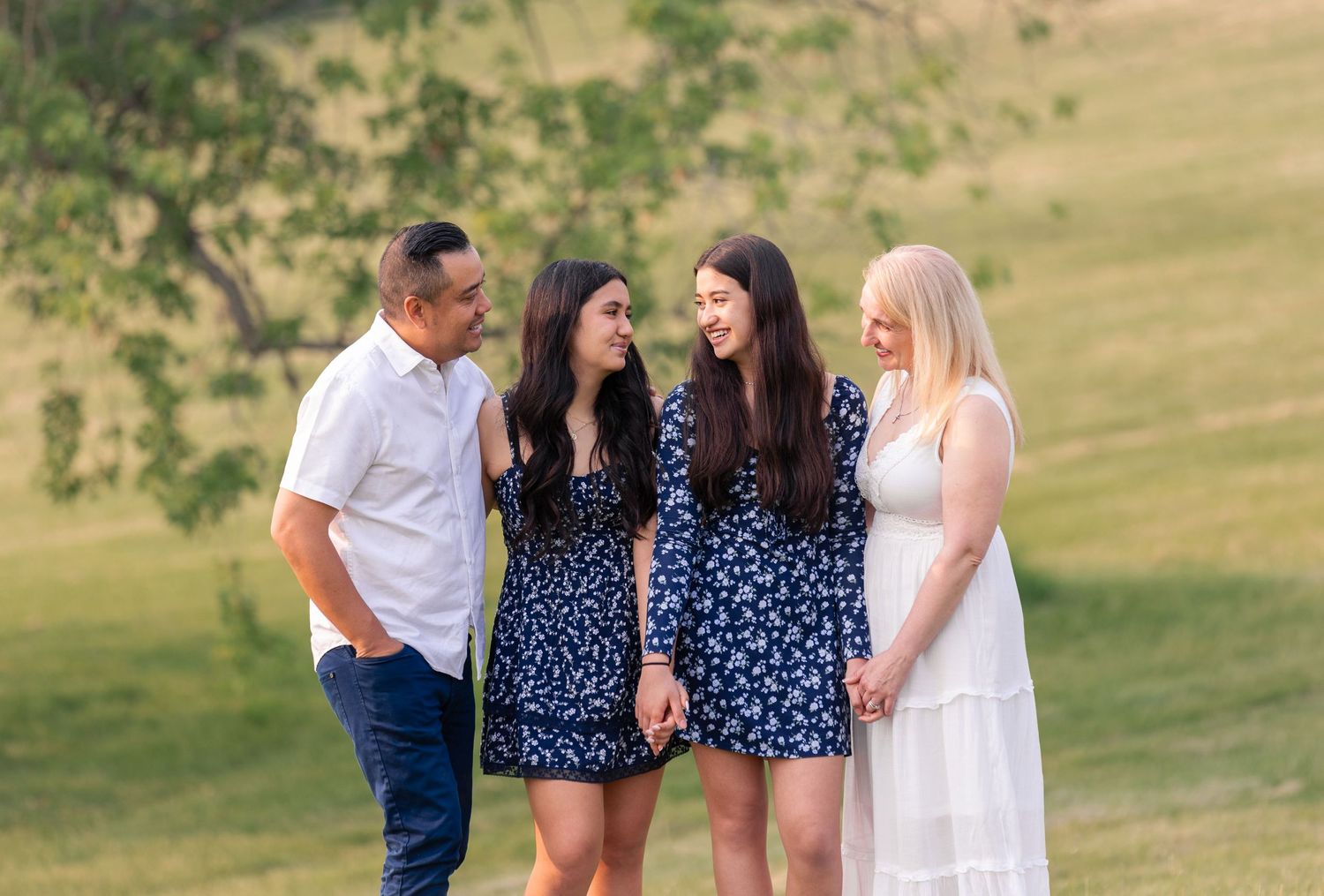 Family photoshoot outdoors in a grassy field with coordinated navy blue and white outfits.