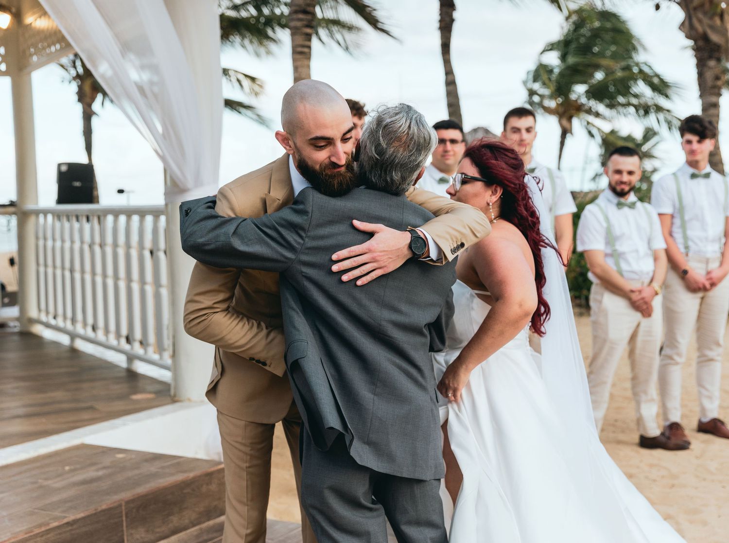 Wedding celebration candid moments captured on beach deck with palm trees.