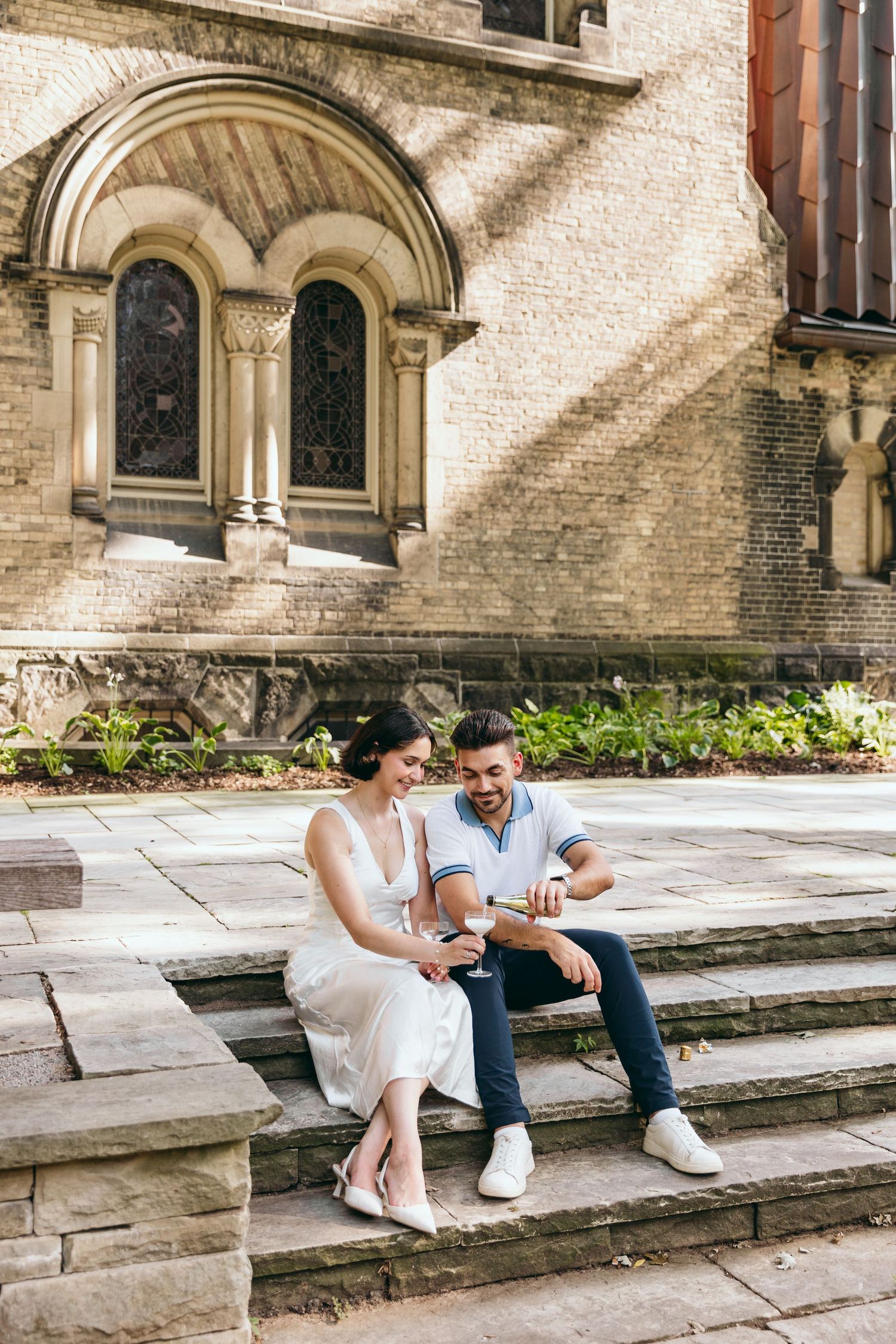 Couple sitting on stone steps outside a historic church building.