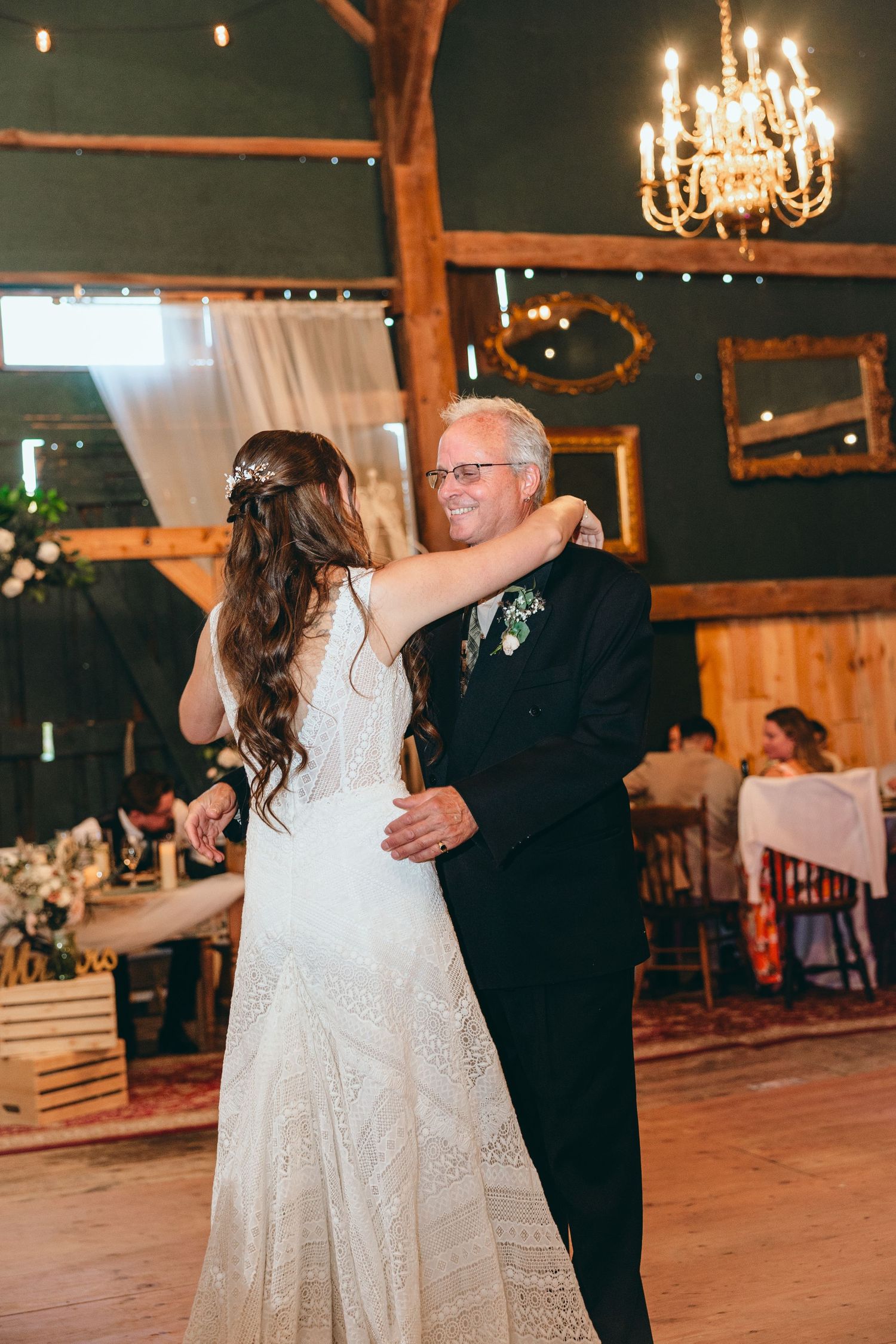 Dancing couple sharing a special moment on wooden dance floor under chandelier lighting.