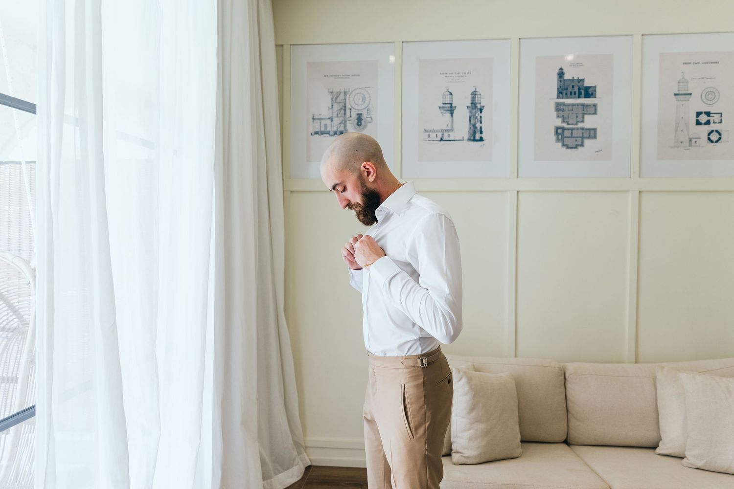 Side view of a person in white shirt and beige pants in an elegant room with wall art.