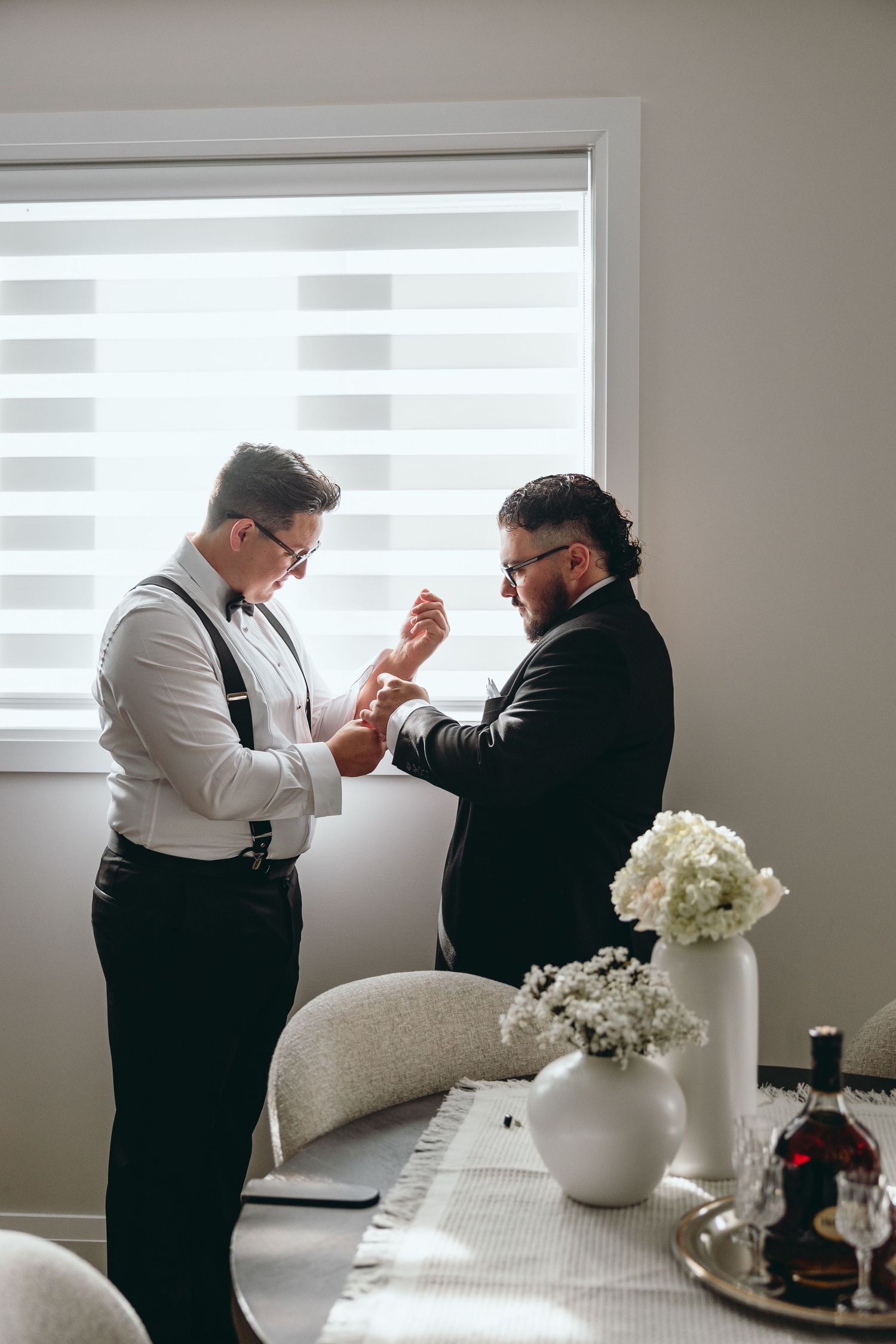 Two people in formal wear sharing a moment near white floral arrangements.
