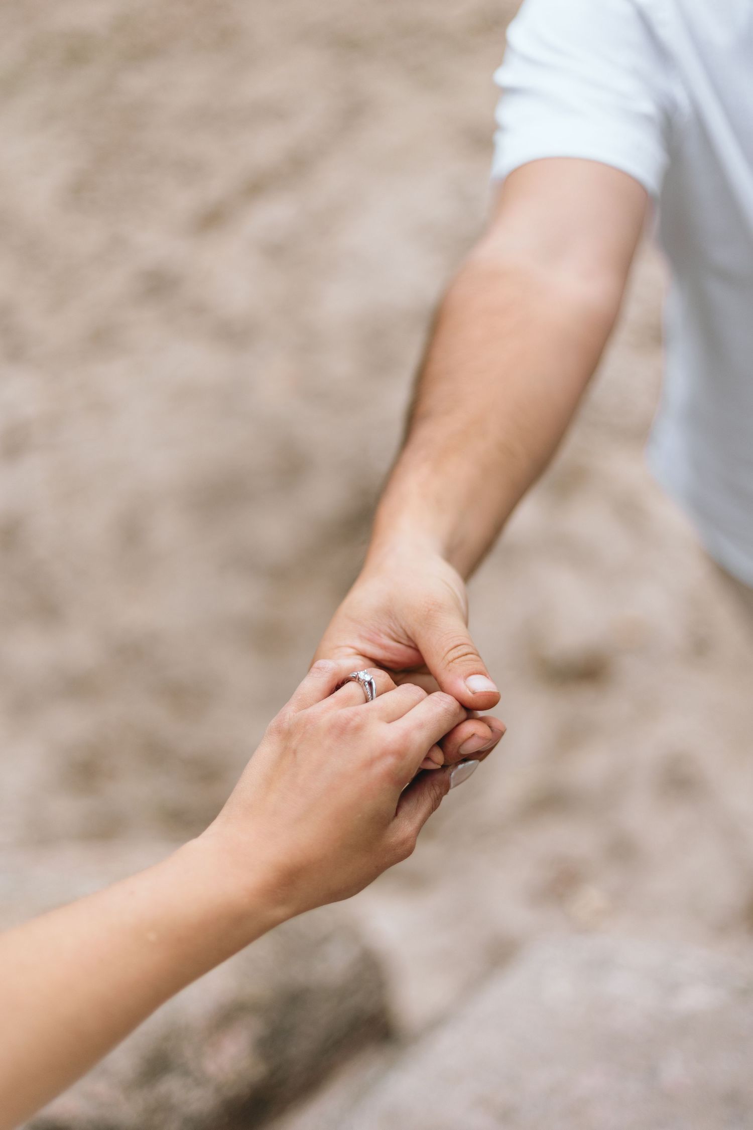 Close-up shot of two hands clasped together showing an engagement ring.