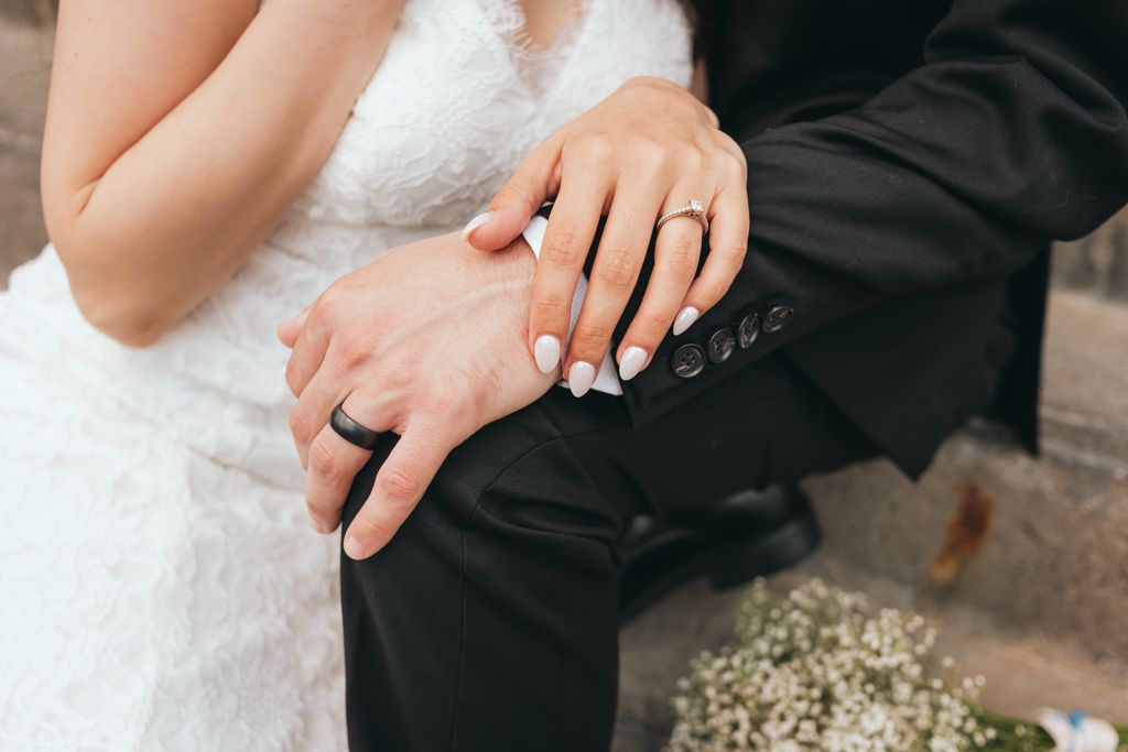 Close-up details of hands and wedding attire during a celebration.