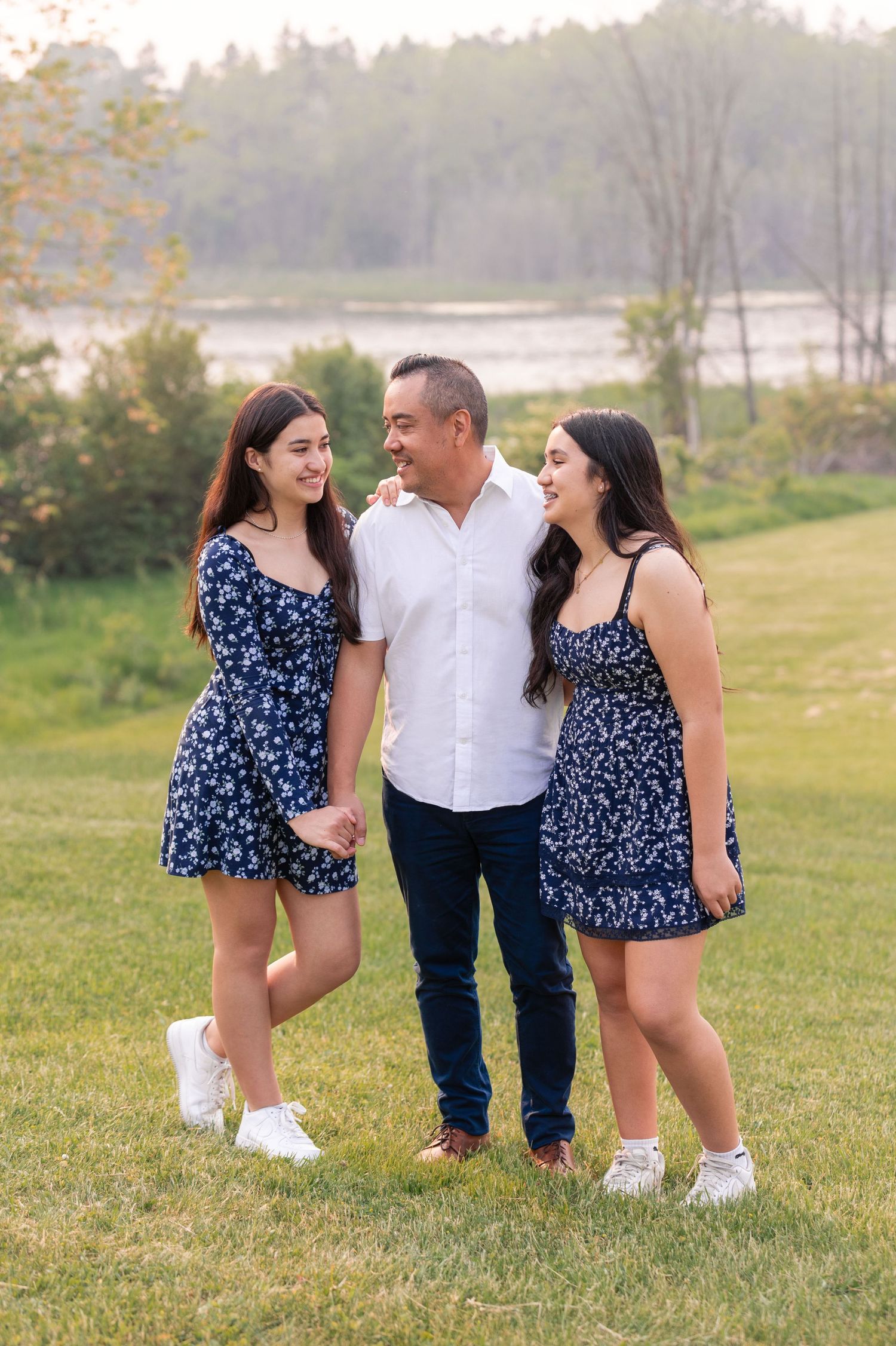 Candid family portraits on a grassy hill during golden hour.