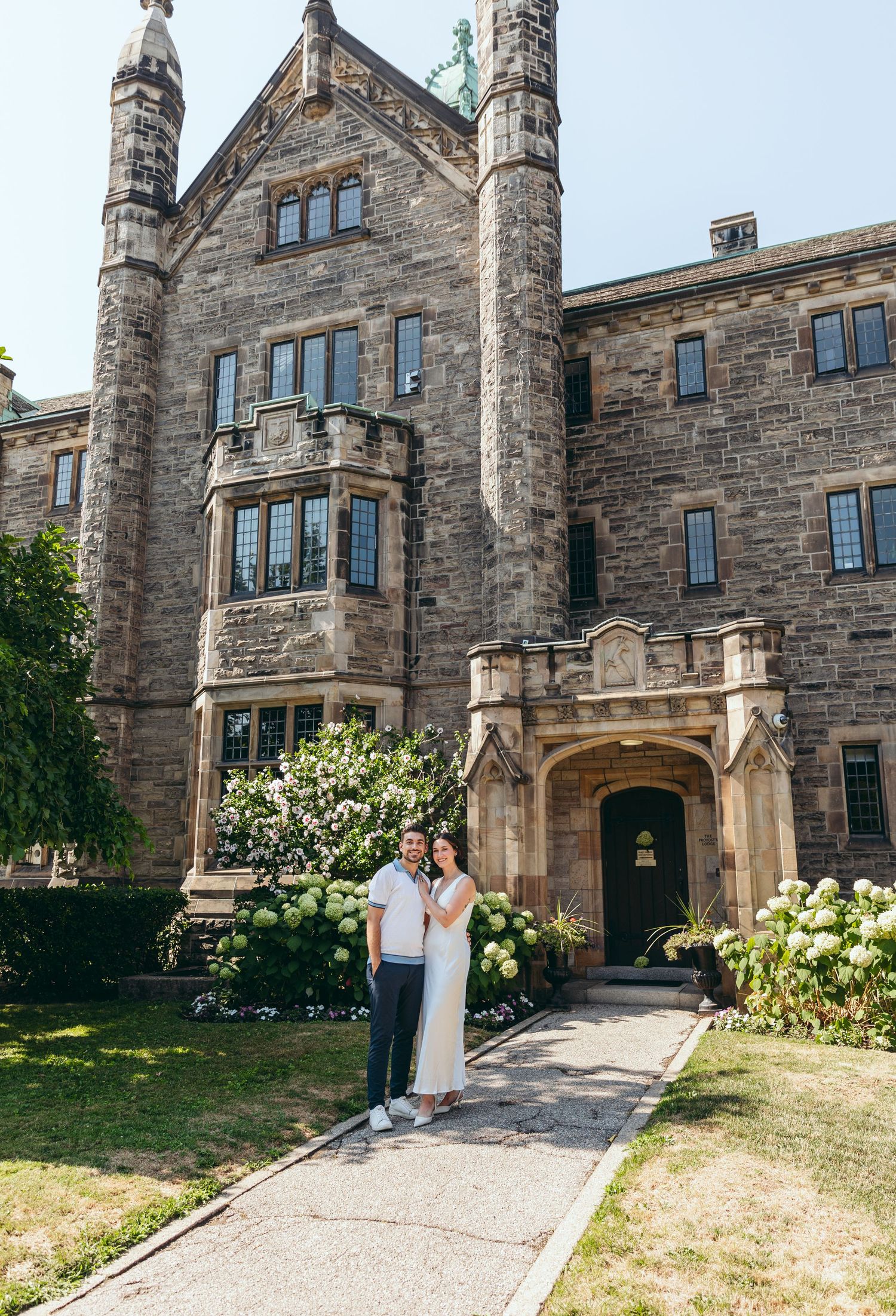 A stone Gothic building entrance with ornate architecture and landscaped grounds.