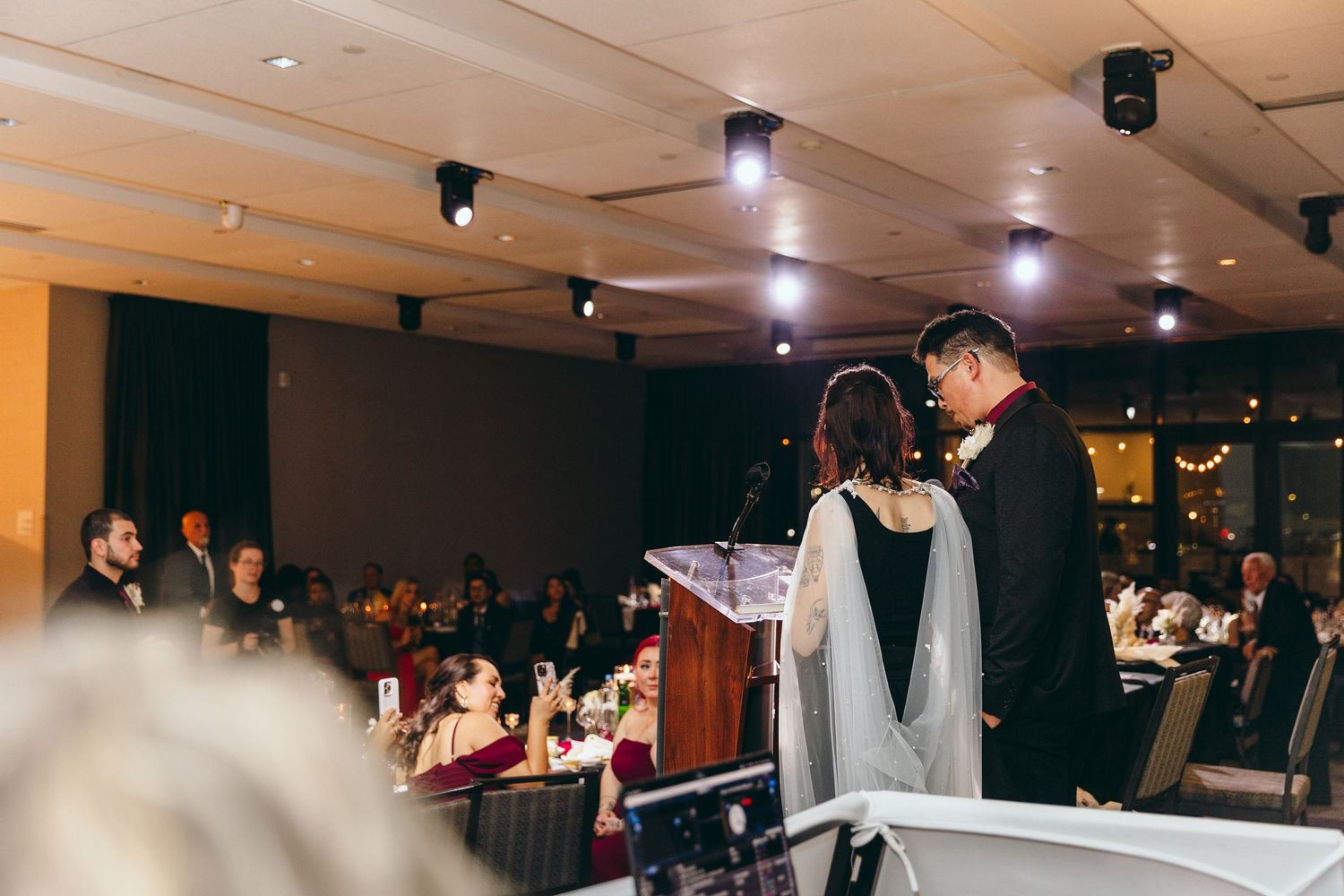 Dimly lit wedding reception venue with track lighting and dance floor setup.