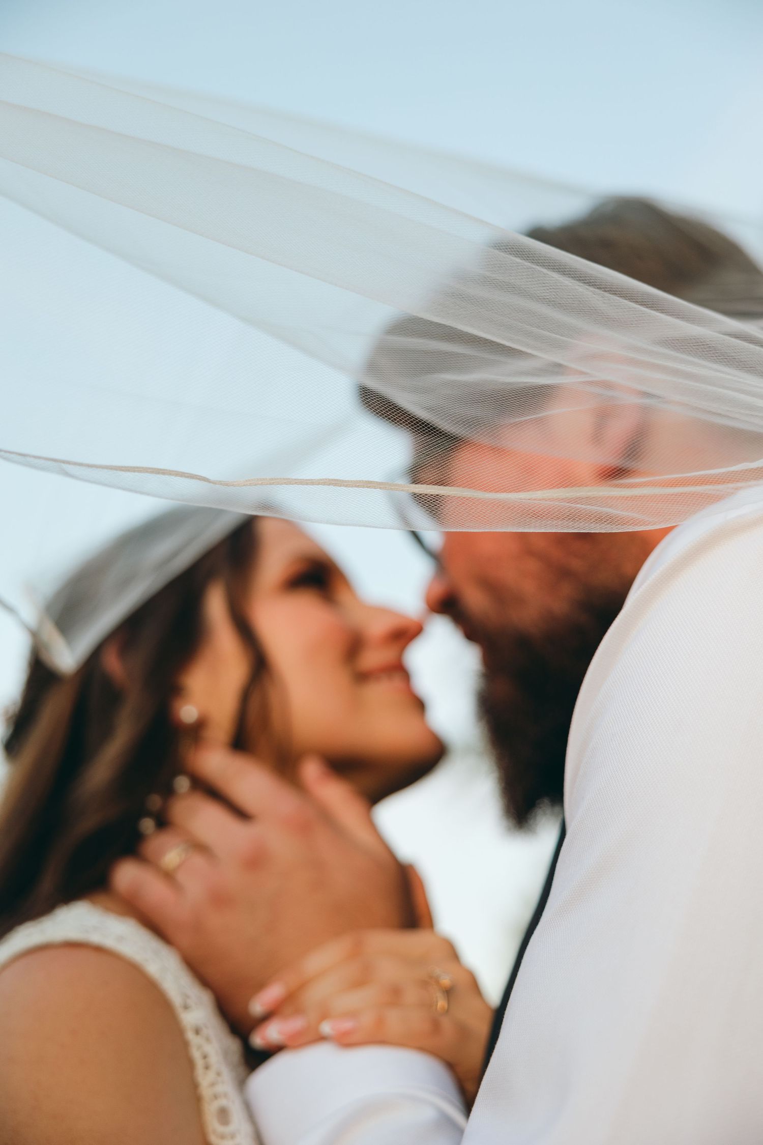 Artistic wedding photos with flowing veil creating romantic ethereal effects.