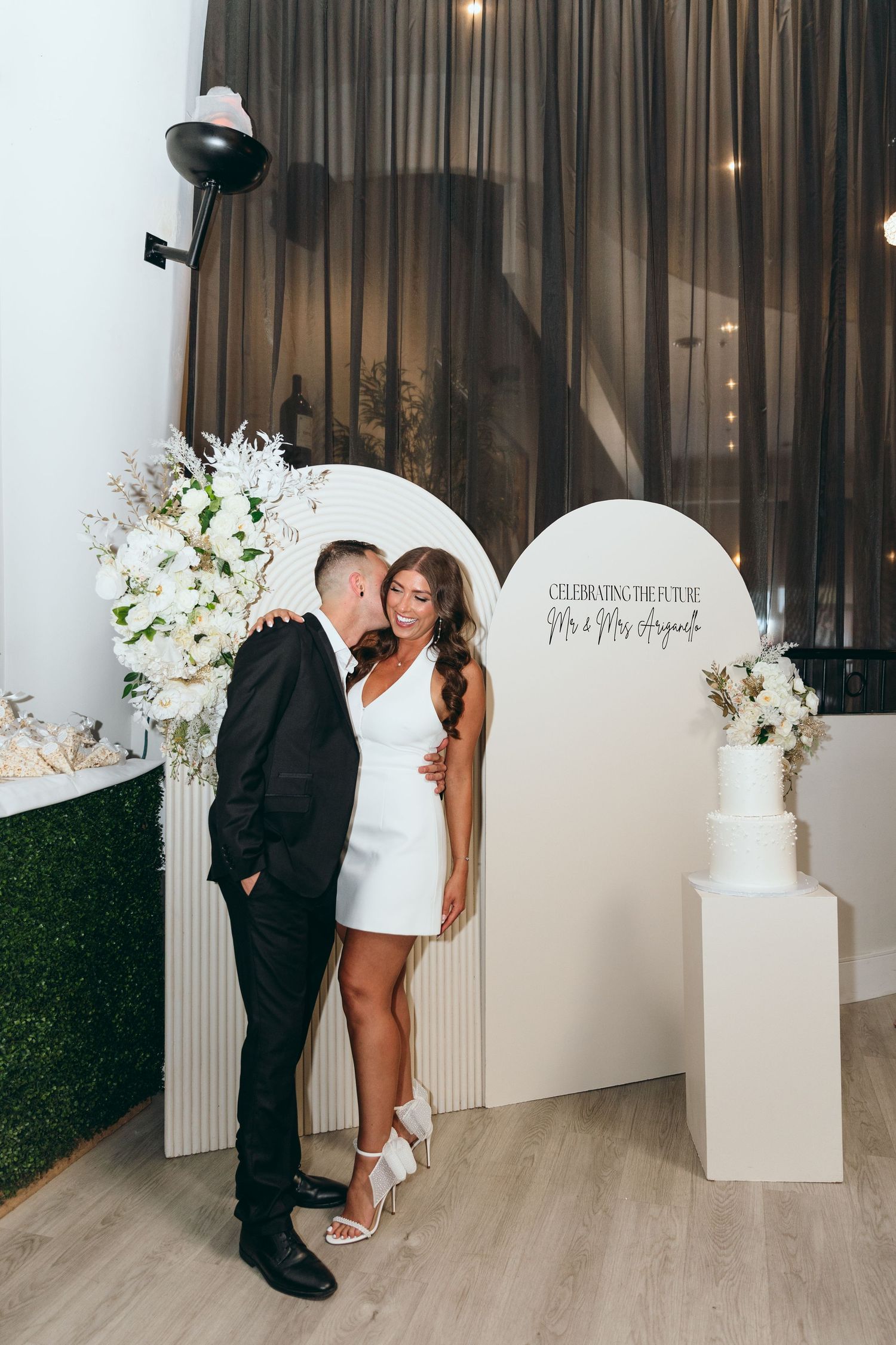 Wedding photo backdrop with white architectural elements and floral arrangements.