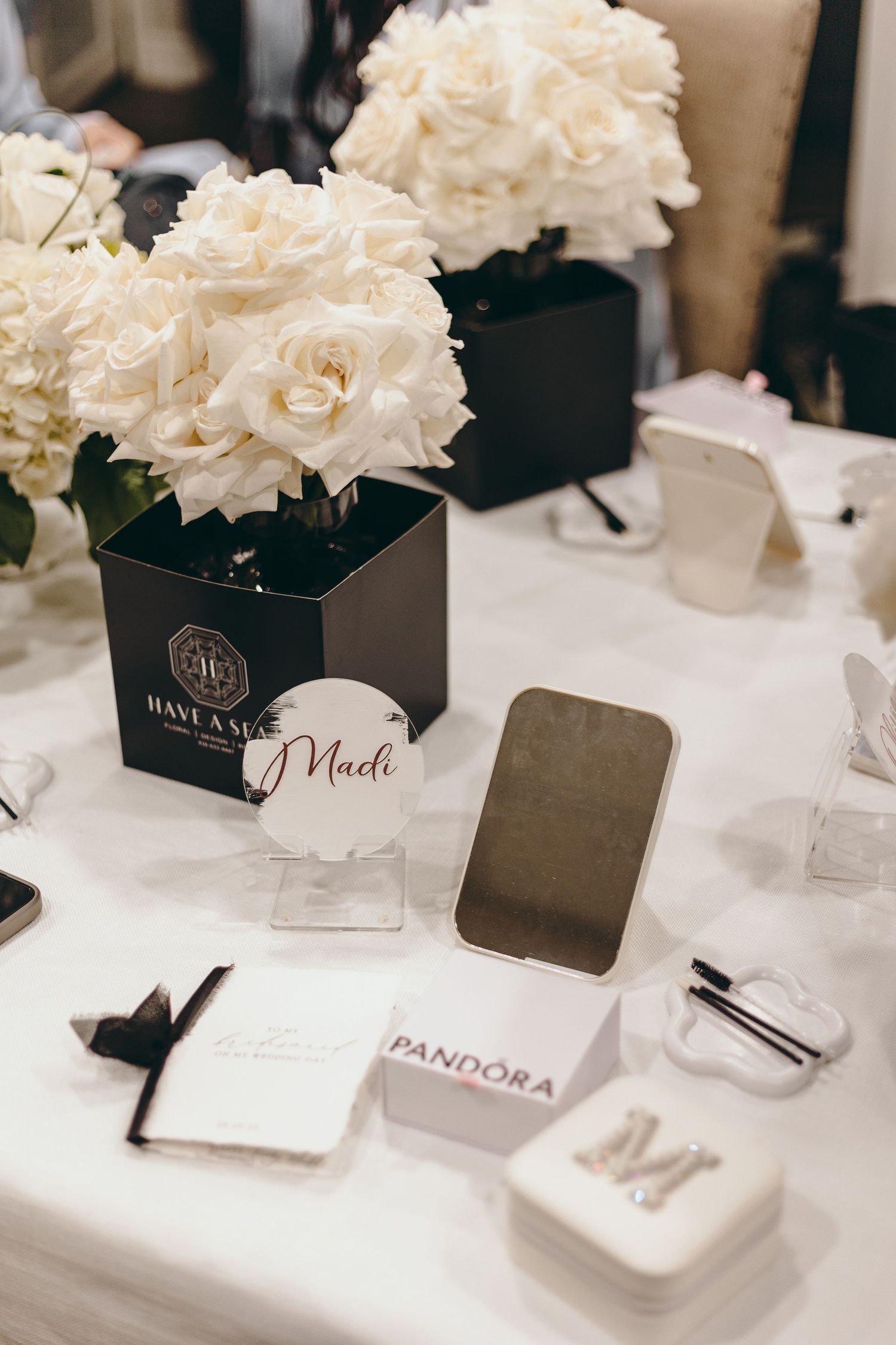 Wedding reception table details with white floral centerpieces and place cards in black holders.