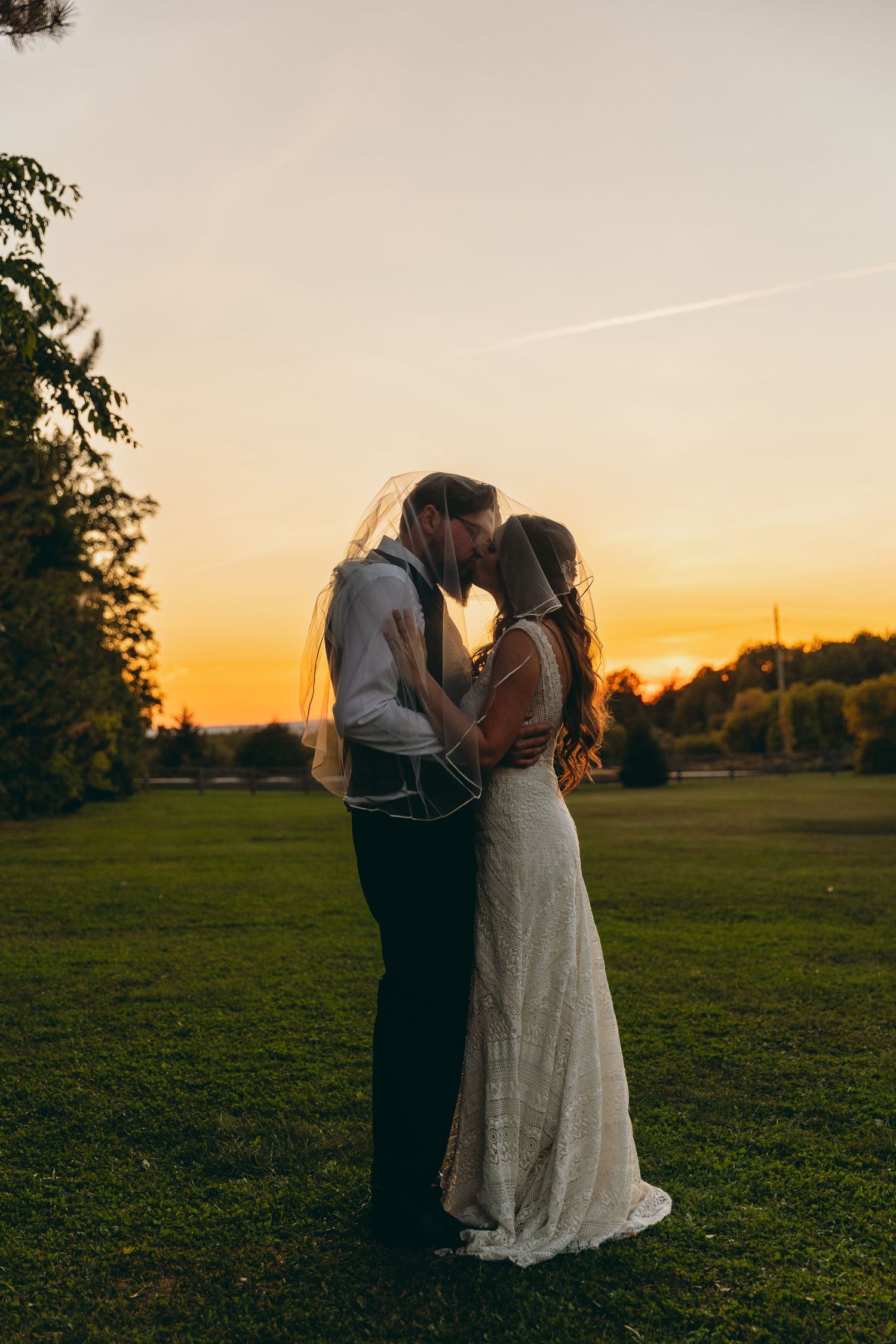 Romantic sunset wedding portrait showing a couple embracing in a golden-lit field.