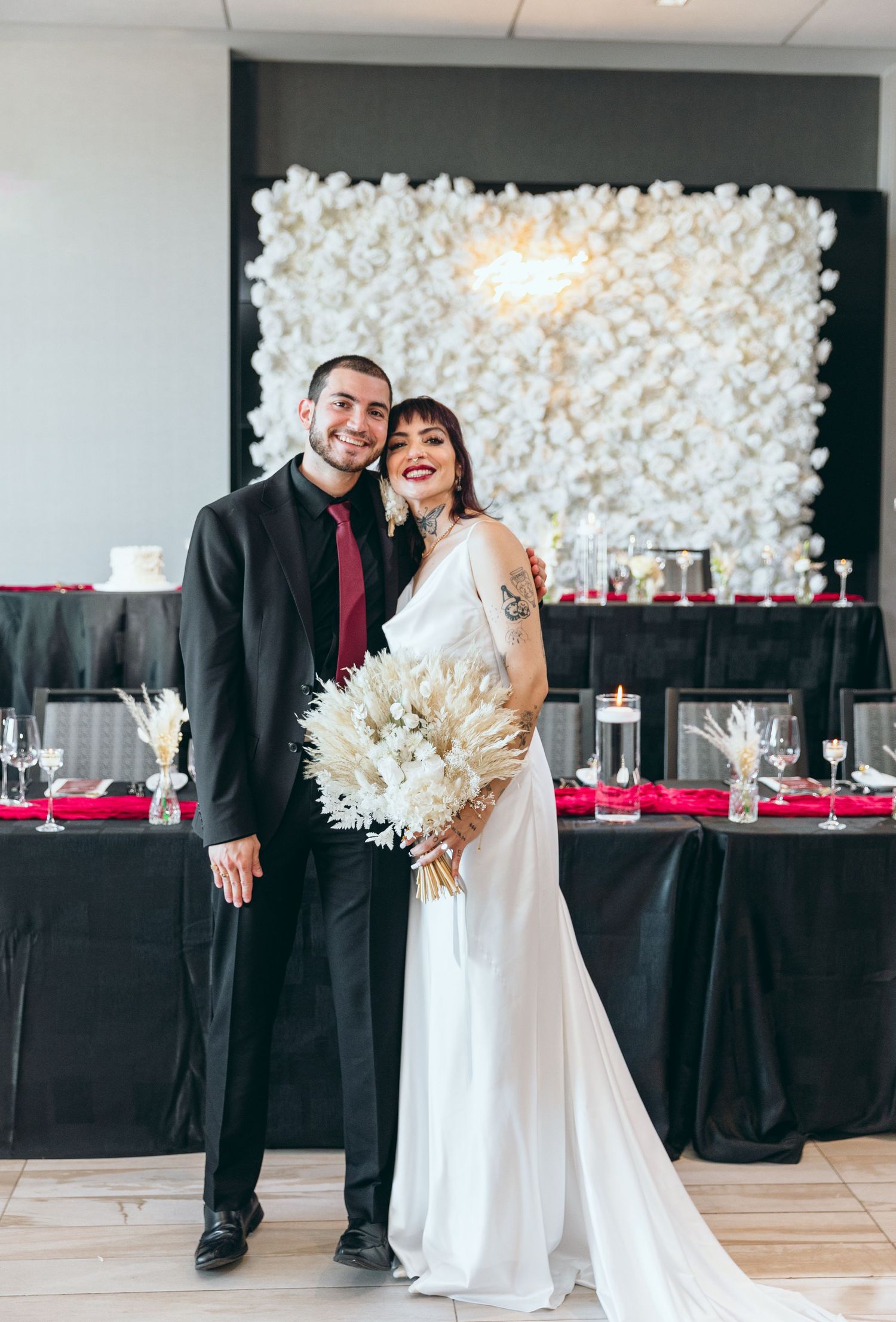 Wedding celebration candid moments captured in front of white flower wall and reception tables.