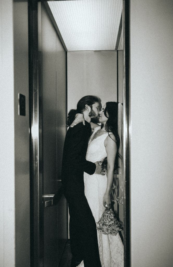 Black and white photo of couples in formal wear standing in a modern hallway.