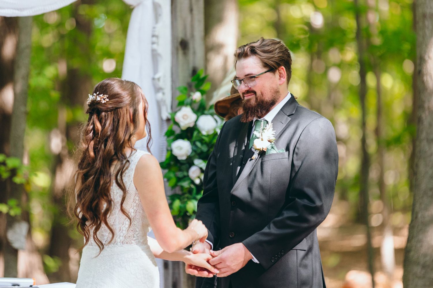 Intimate wedding ceremony moment captured under forest canopy.