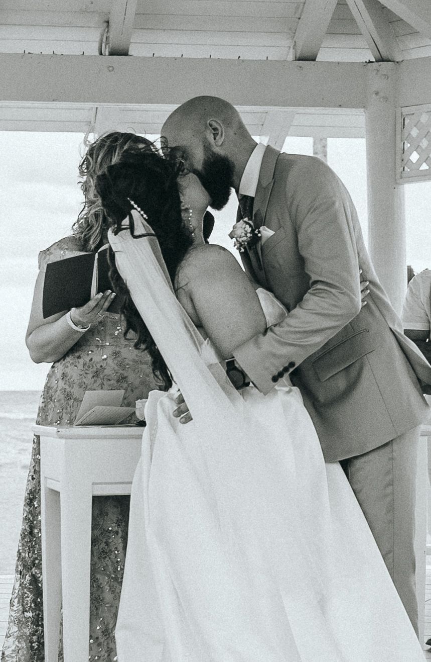 Black and white photo captures romantic moments during a beachside wedding ceremony.