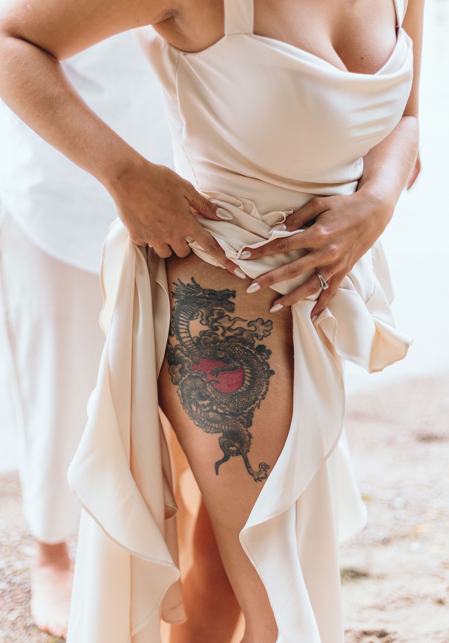 Artistic floral tattoo revealed through flowing white dress fabric.