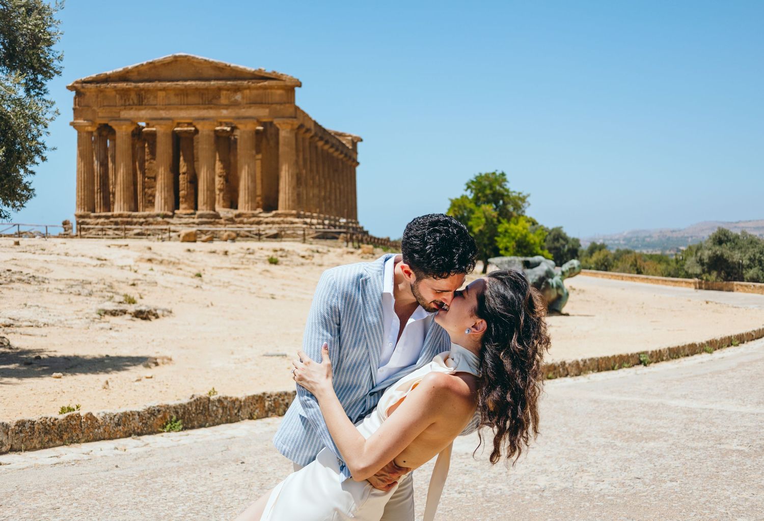 A romantic photoshoot at an ancient temple site with clear blue skies and stone architecture.