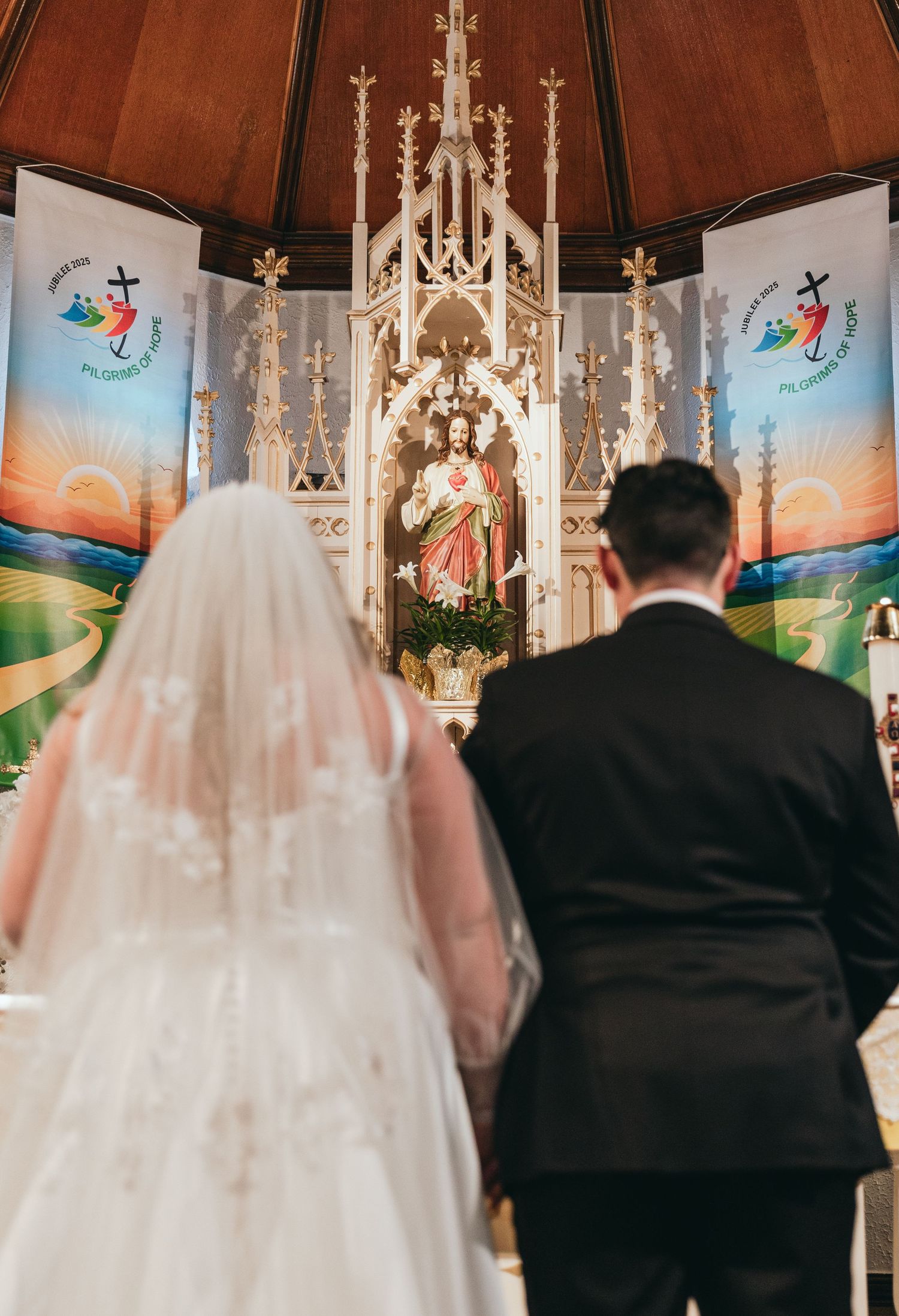 Church wedding ceremony with decorative altar and painted murals in background.