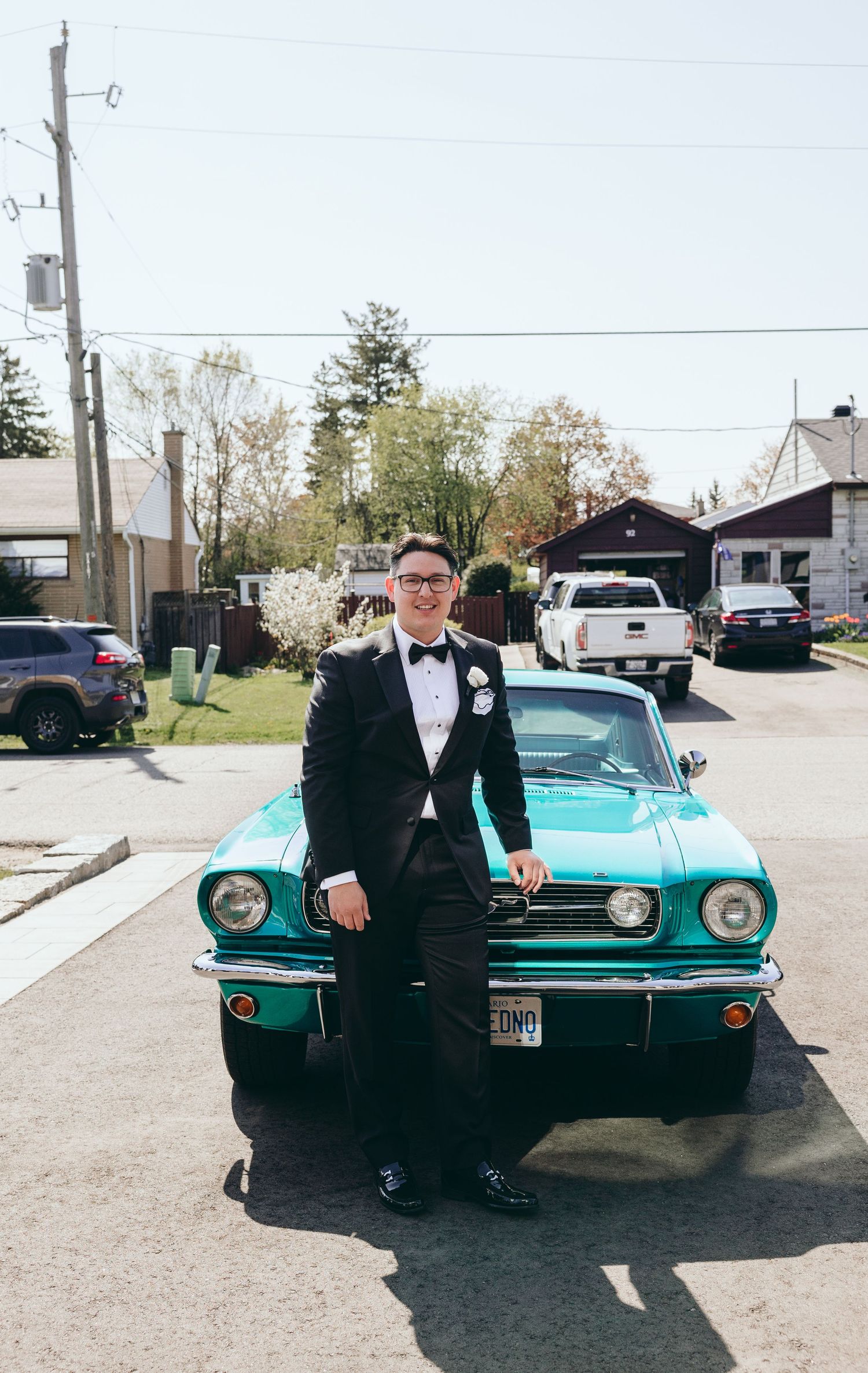 Classic turquoise Mustang convertible parked on a sunny day with formal attire visible.