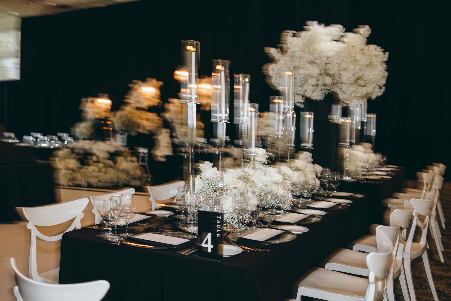 Modern black and white wedding reception table with tall candle centerpieces and floral arrangements.