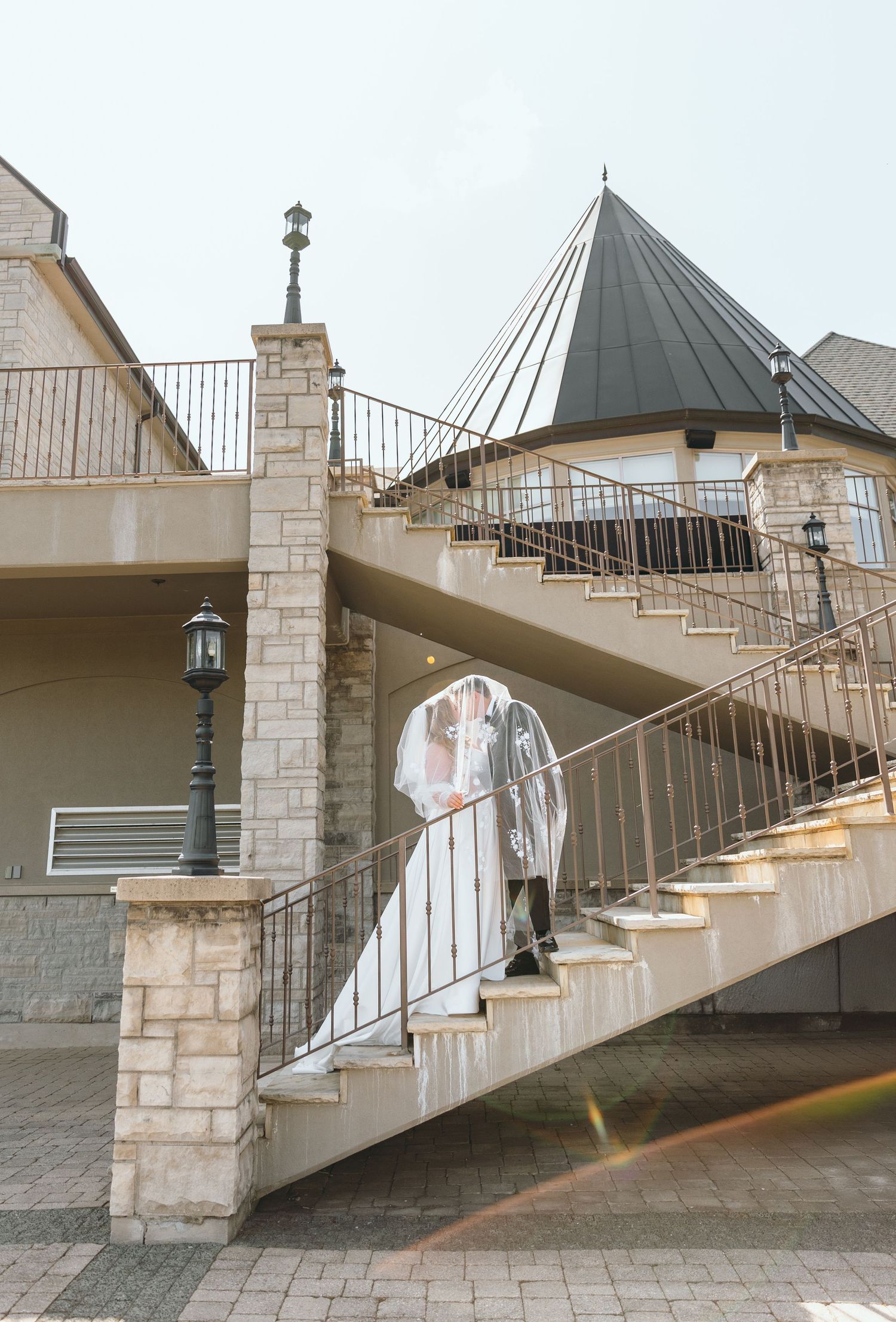 Architectural detail of stone staircase with curved railings and domed roof at wedding venue.