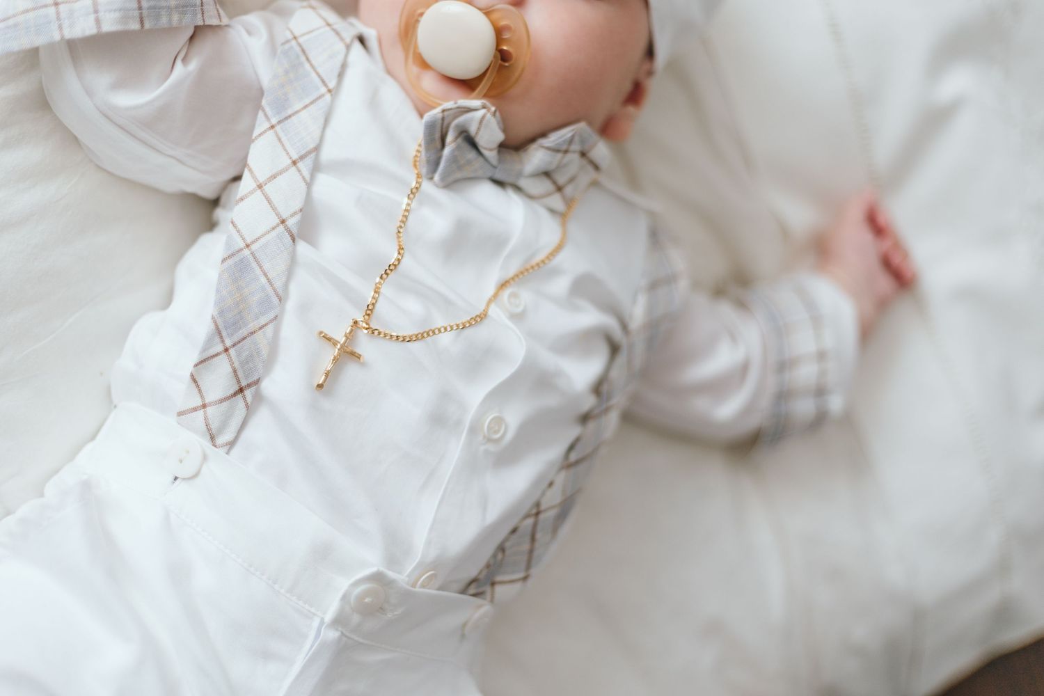Close-up details of delicate white baptismal gown with intricate embroidery.