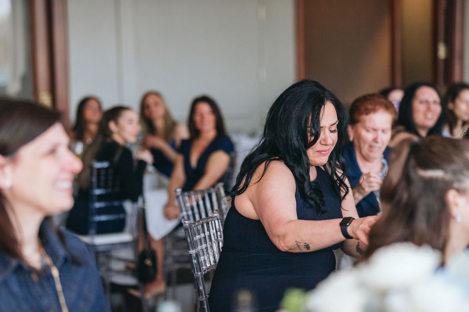 Wedding reception guests gathered at tables decorated with white floral arrangements.
