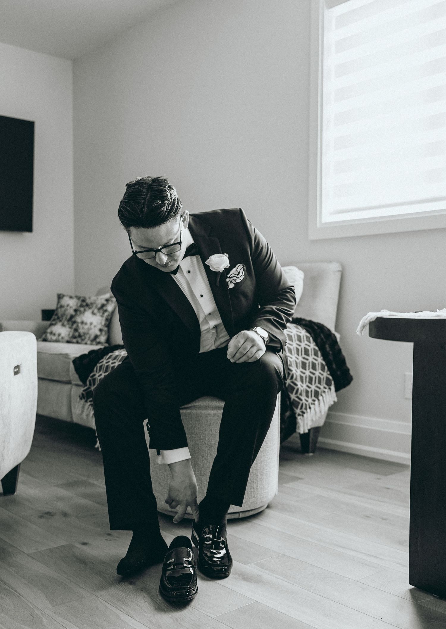 Black and white photos showing emotional moments of preparation in a bright modern room.