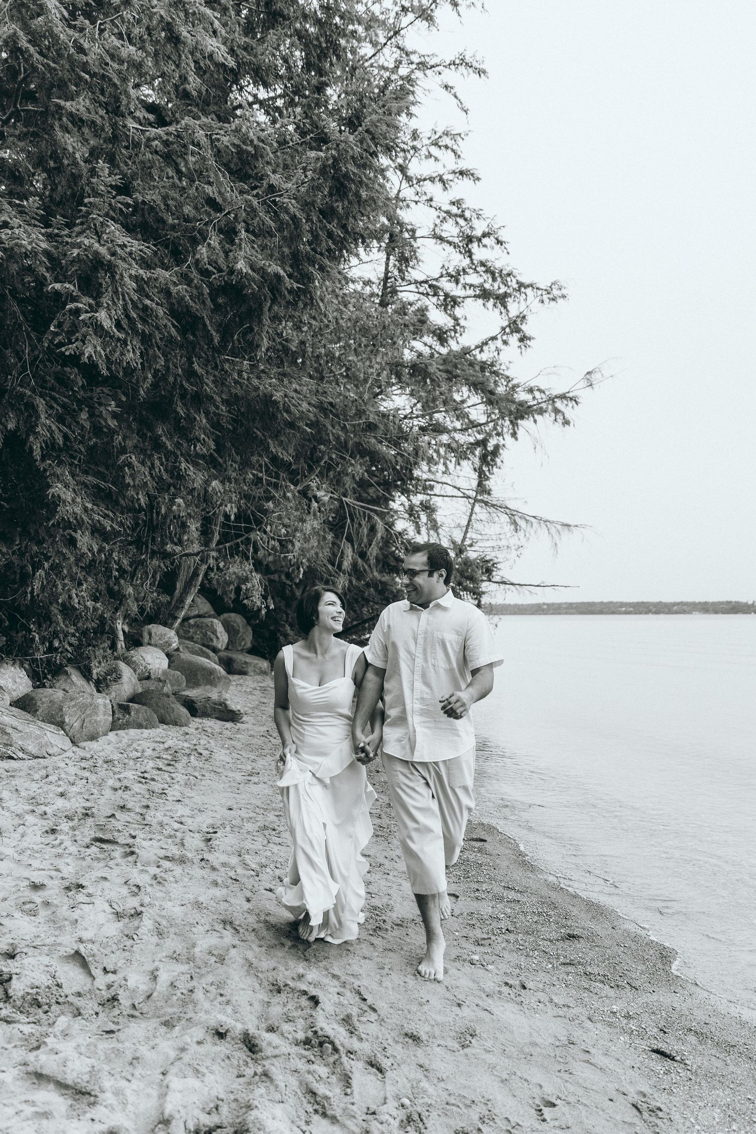 A couple walking hand in hand along a scenic waterfront path.