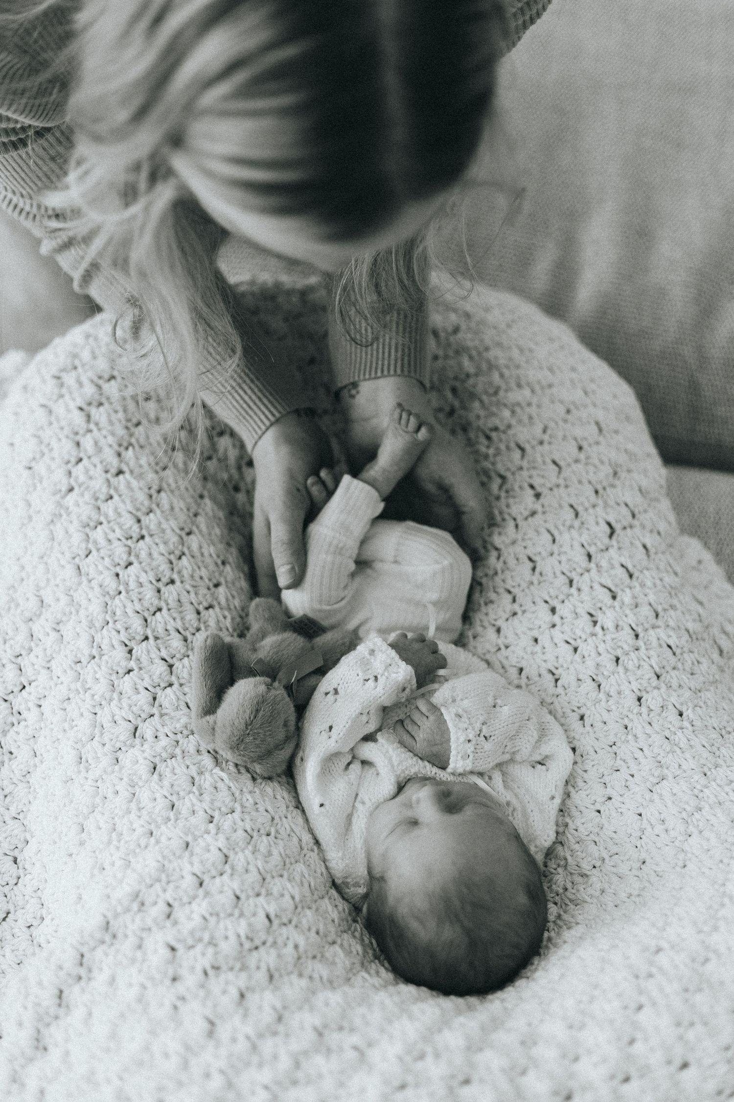 Black and white photo series of a newborn baby lying on a textured white blanket.