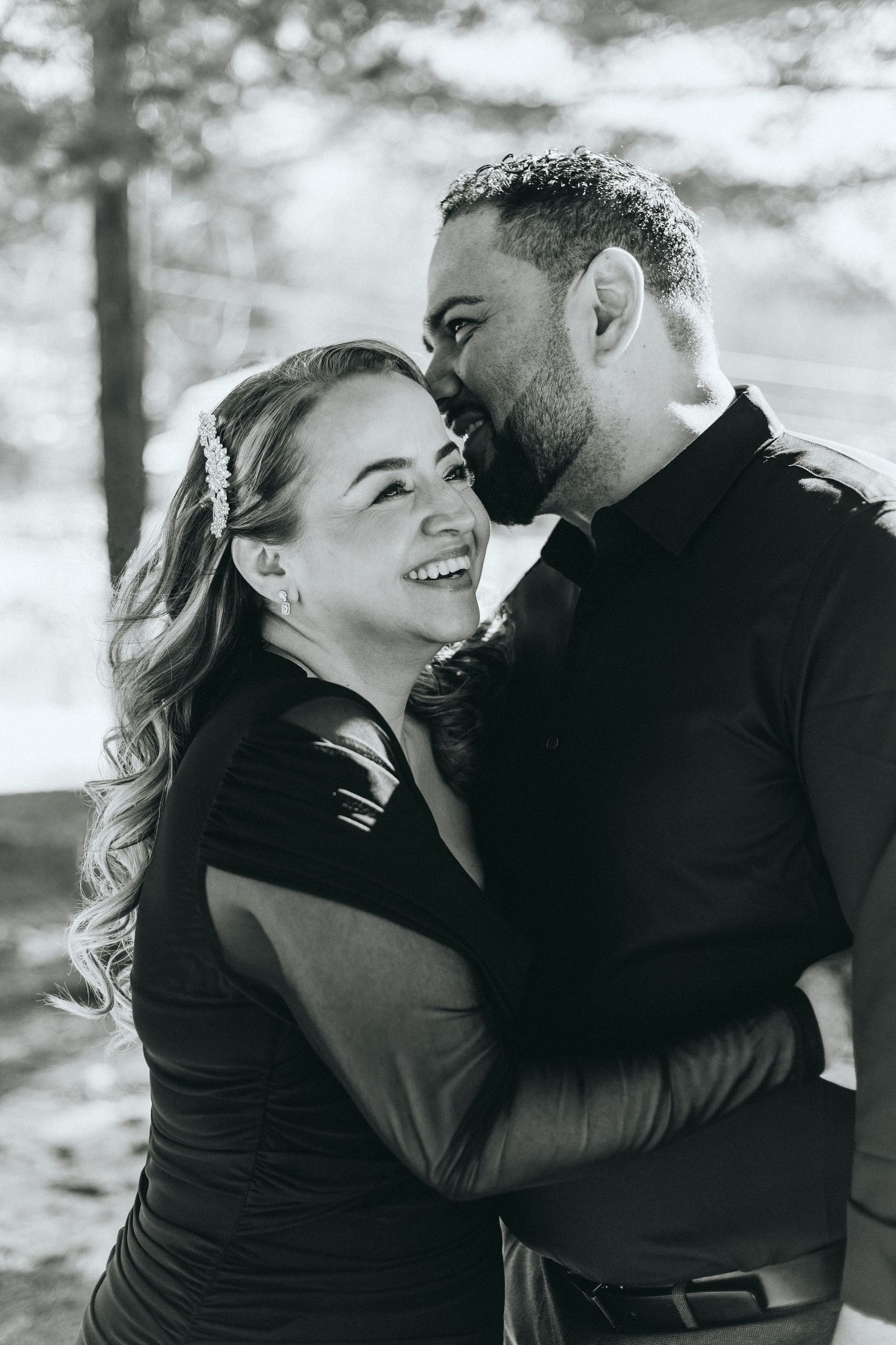 A black and white portrait of a couple sharing a joyful intimate moment.