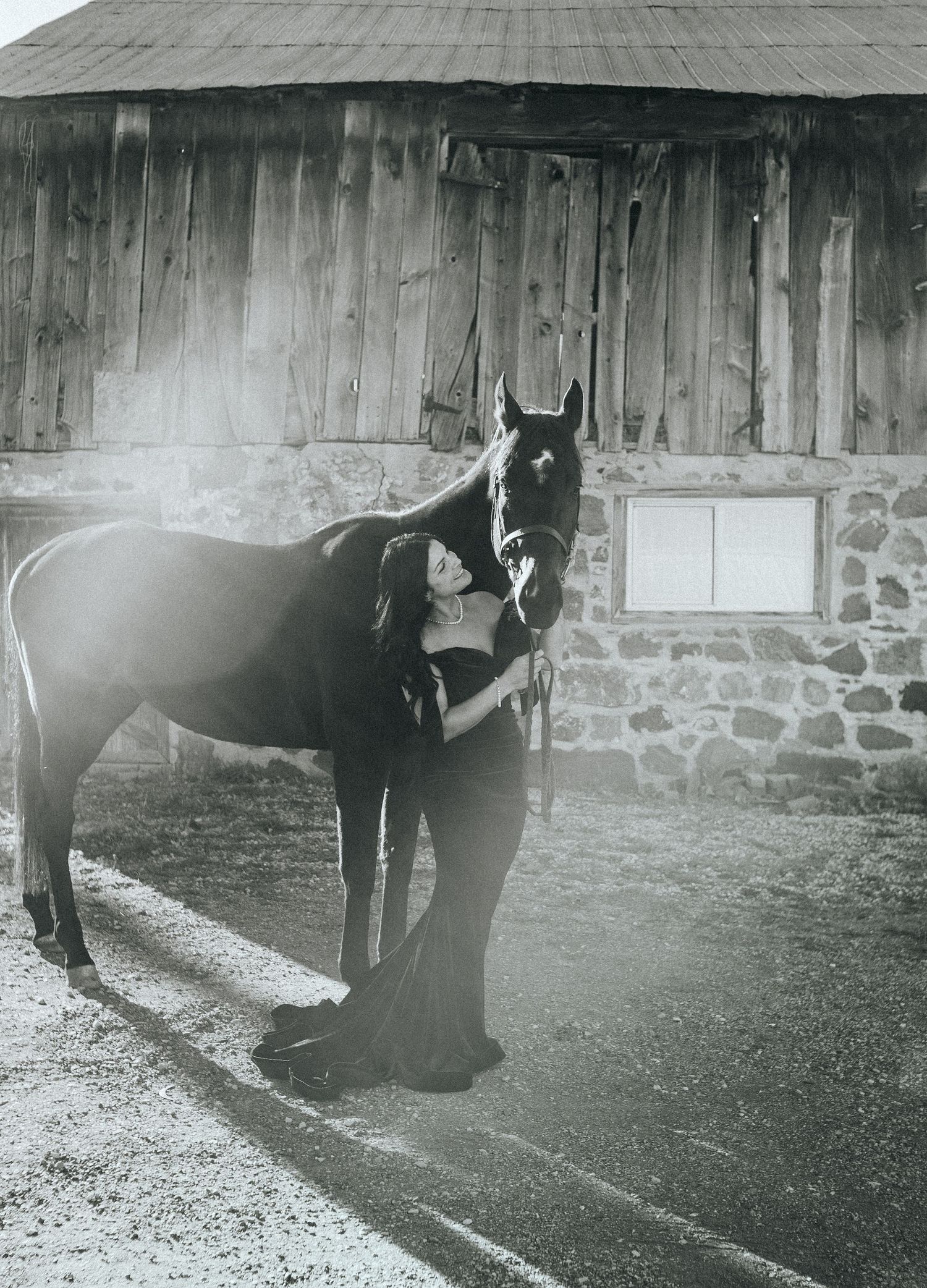 Black and white photo series of horses standing outside a rustic stone barn.
