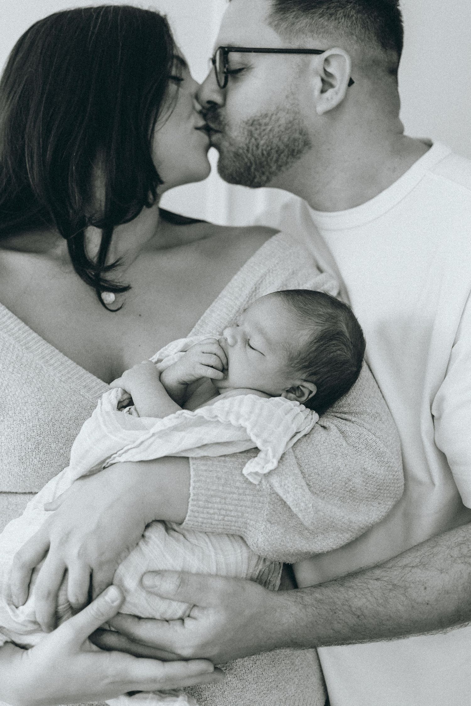 Black and white photos of tender family moments with a sleeping infant.