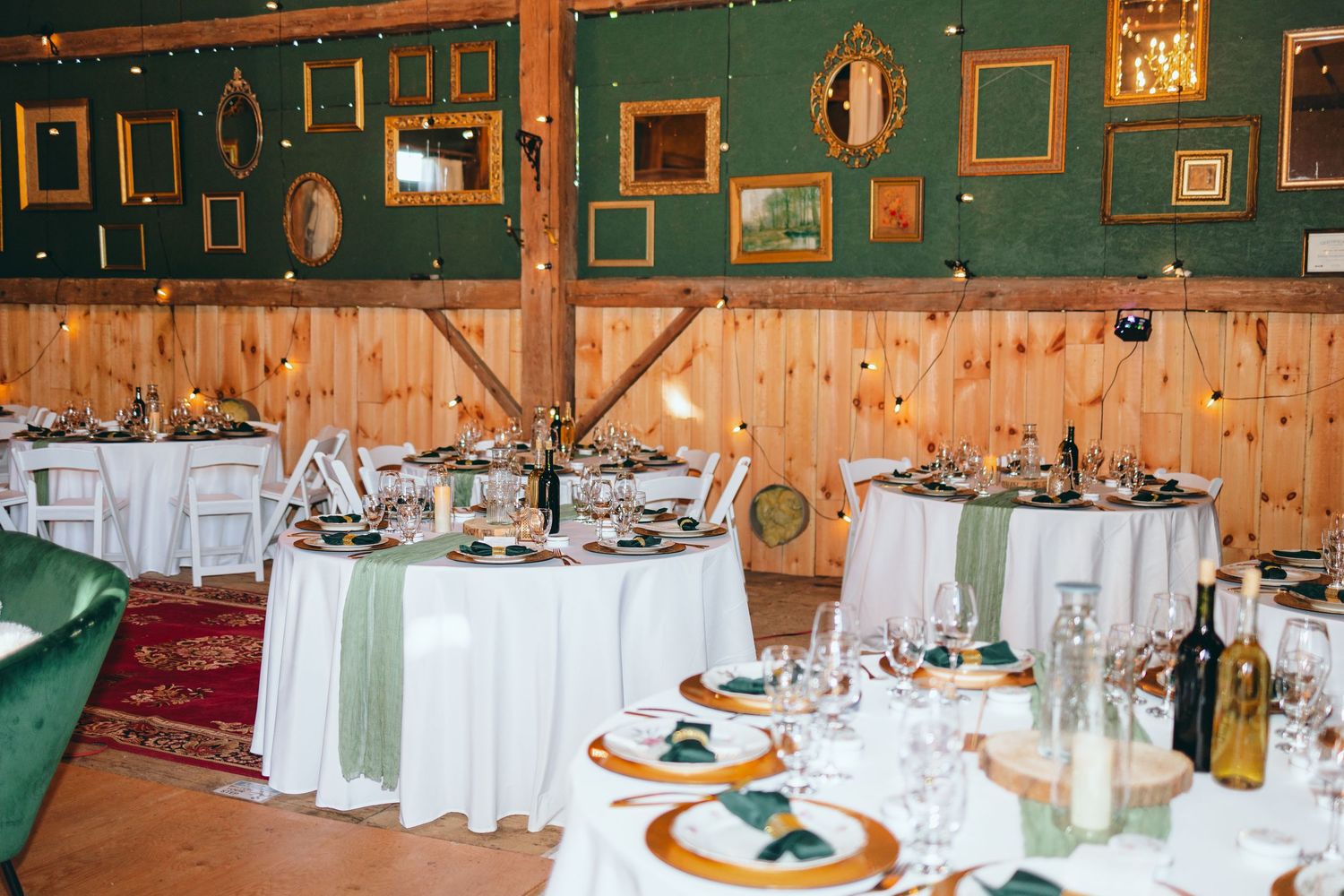Wedding reception venue decorated with rustic green walls and framed photos.