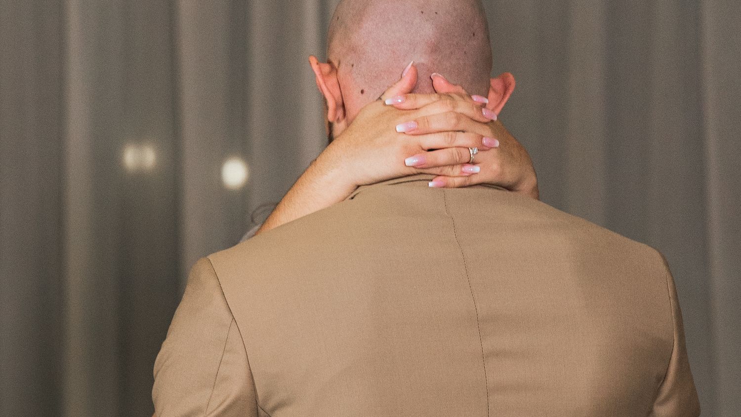 Couple embraces during their first dance at a wedding reception with guests watching.