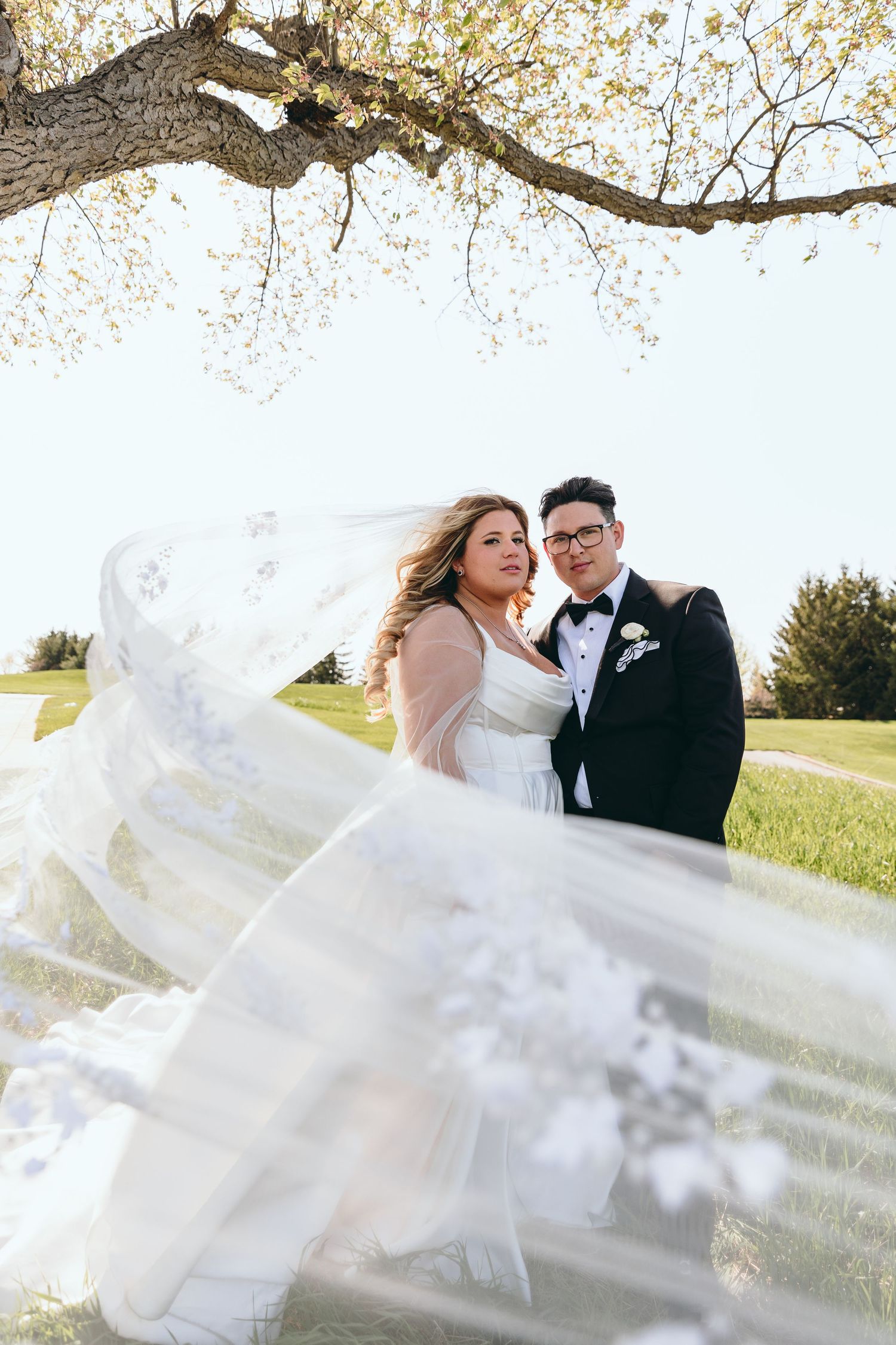 A delicate lace veil flows in the breeze during an outdoor wedding photoshoot.