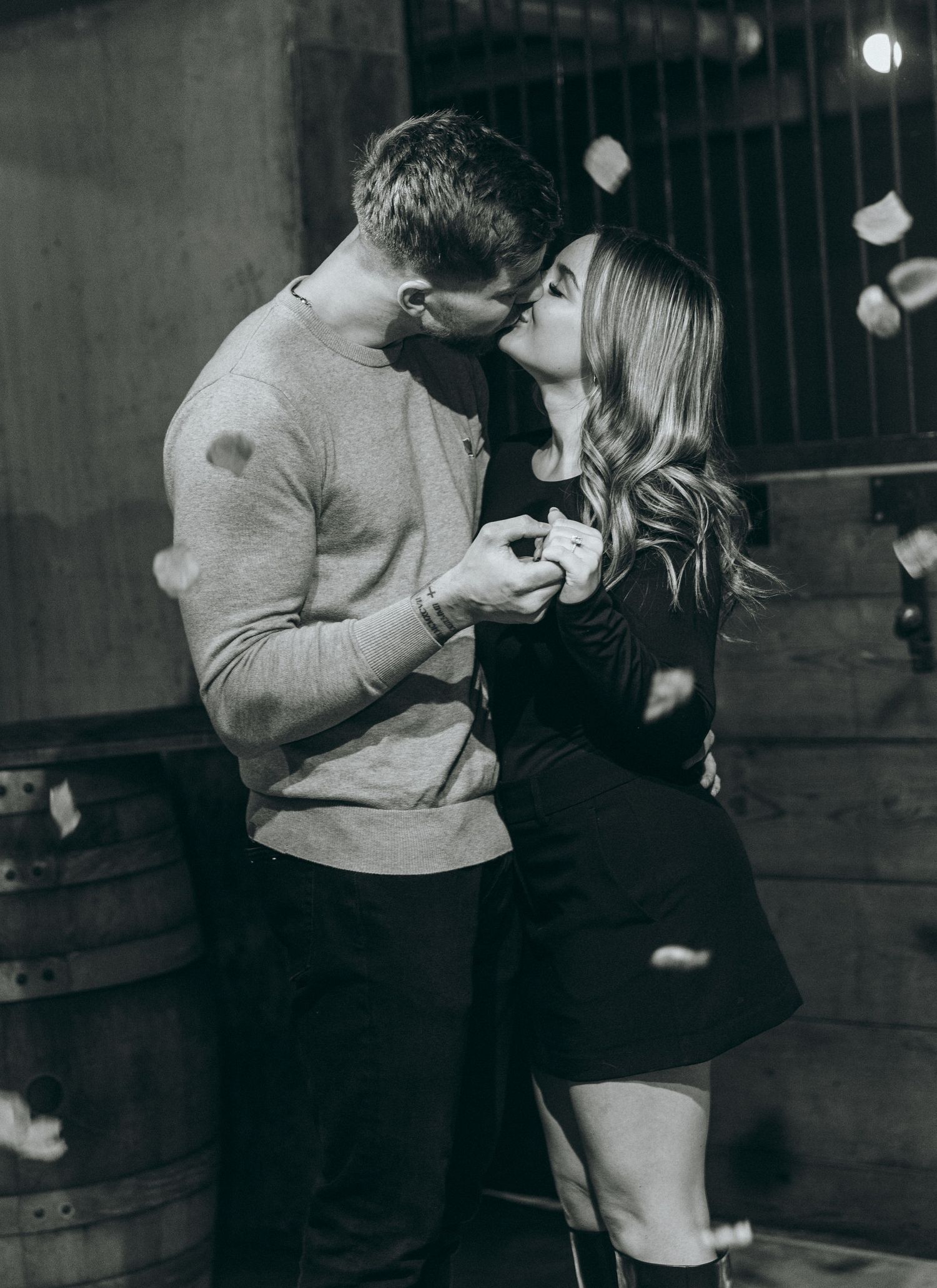 A couple sharing a romantic moment in a wine cellar during a proposal.