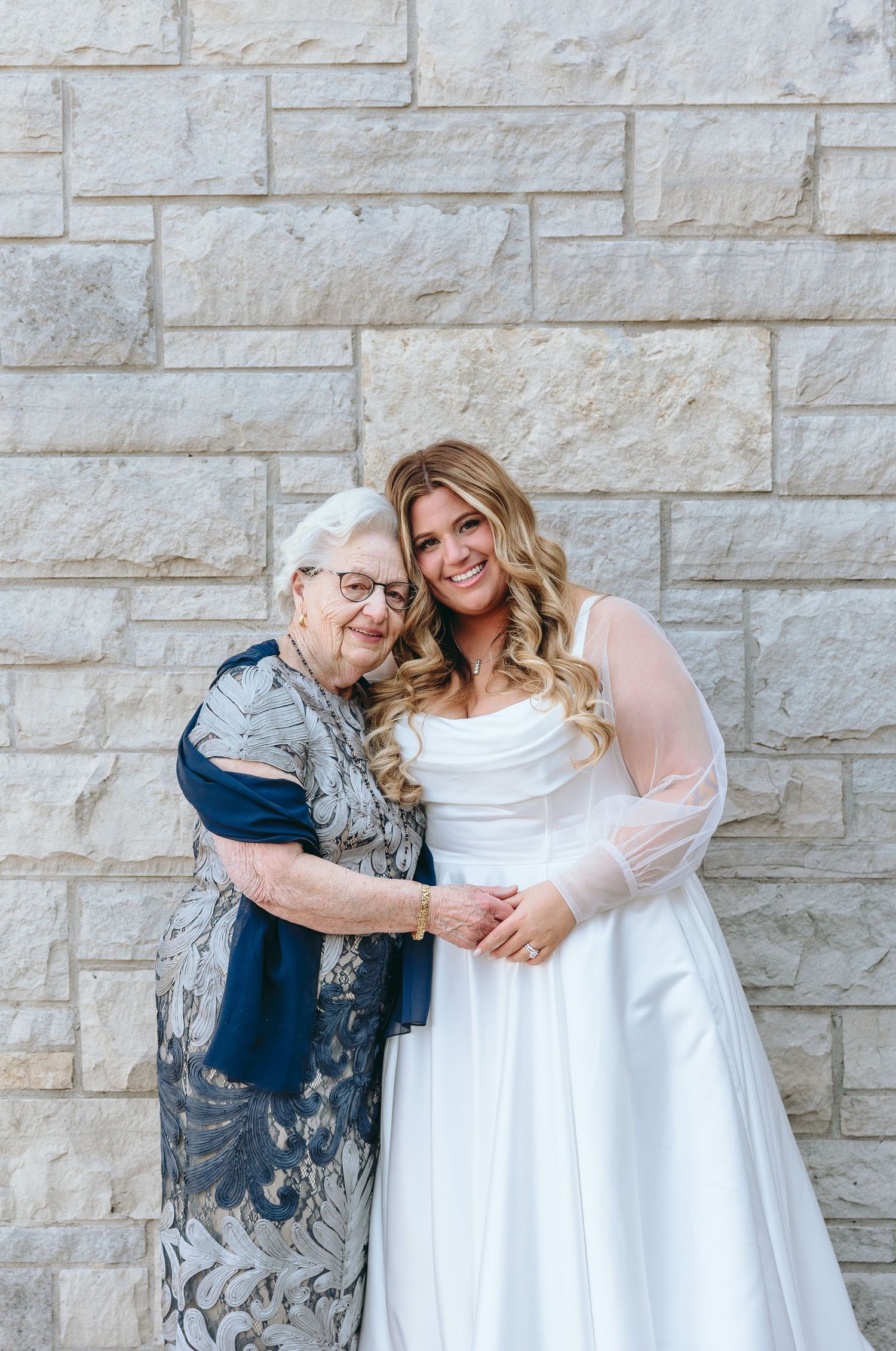 Sweet moment captured against stone wall backdrop.