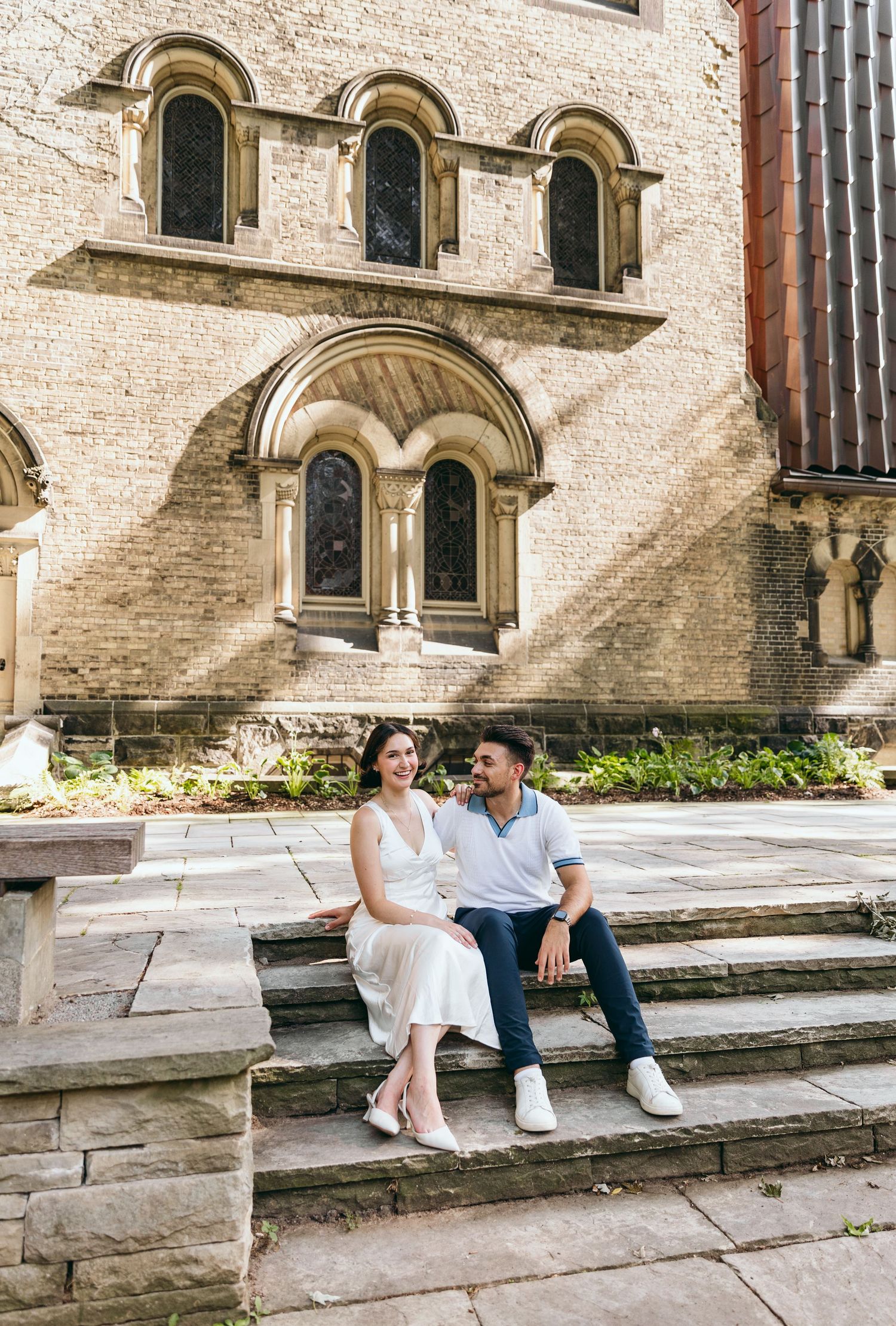 Couple relaxing on stone steps against ornate church architecture.