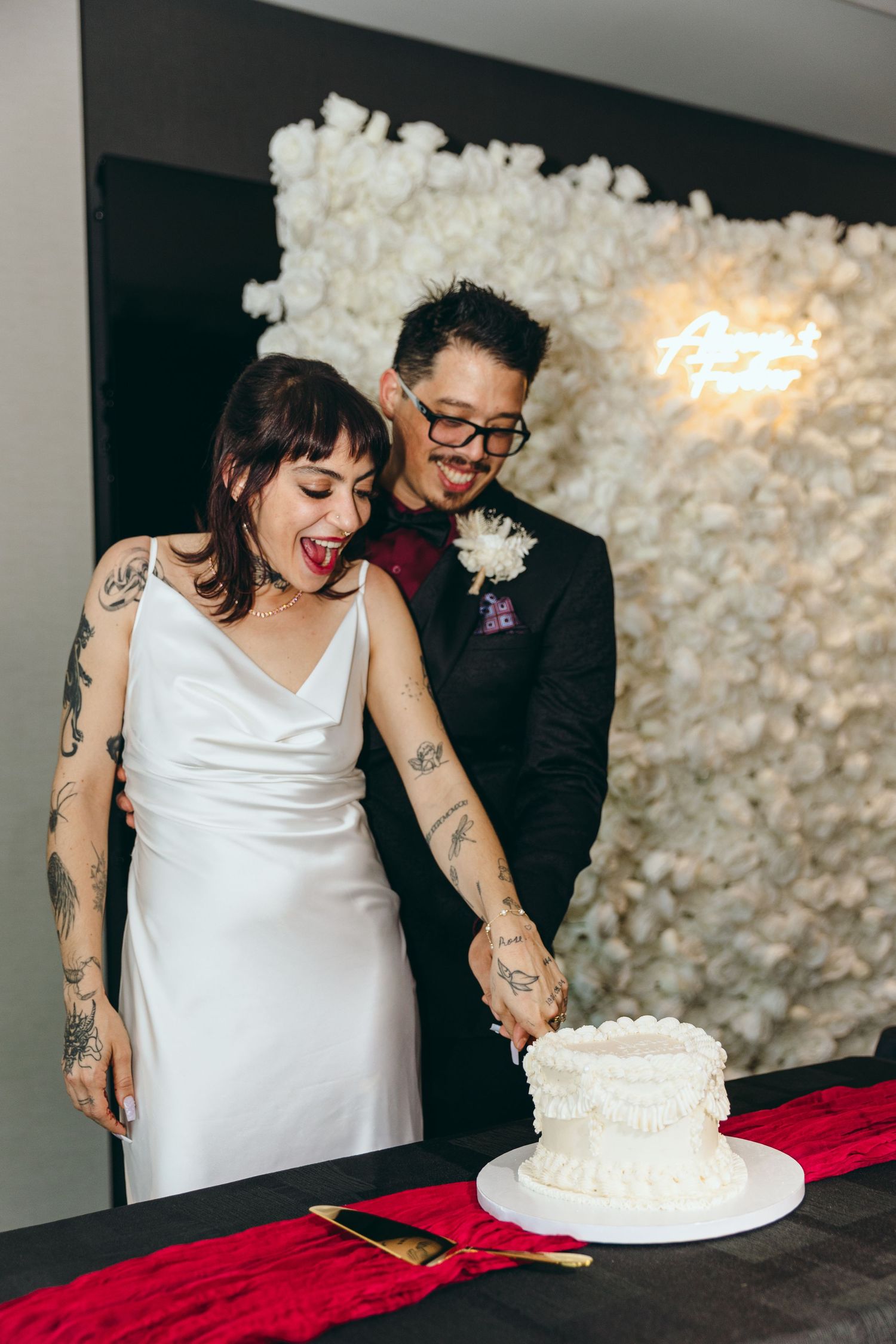 Wedding couple sharing joyful moments while cutting their white wedding cake.