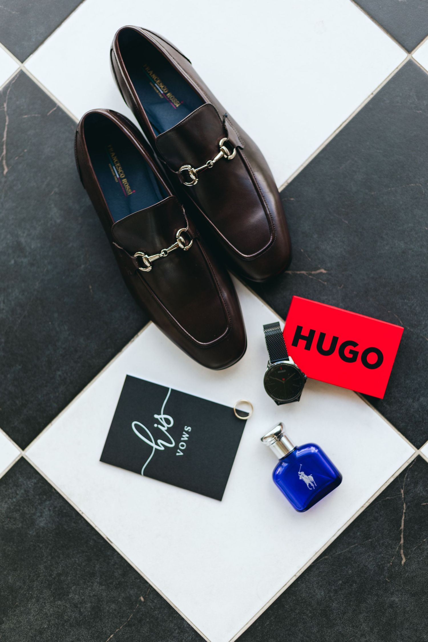 Brown leather loafers with Hugo brand tag and perfume bottle on checkered floor.