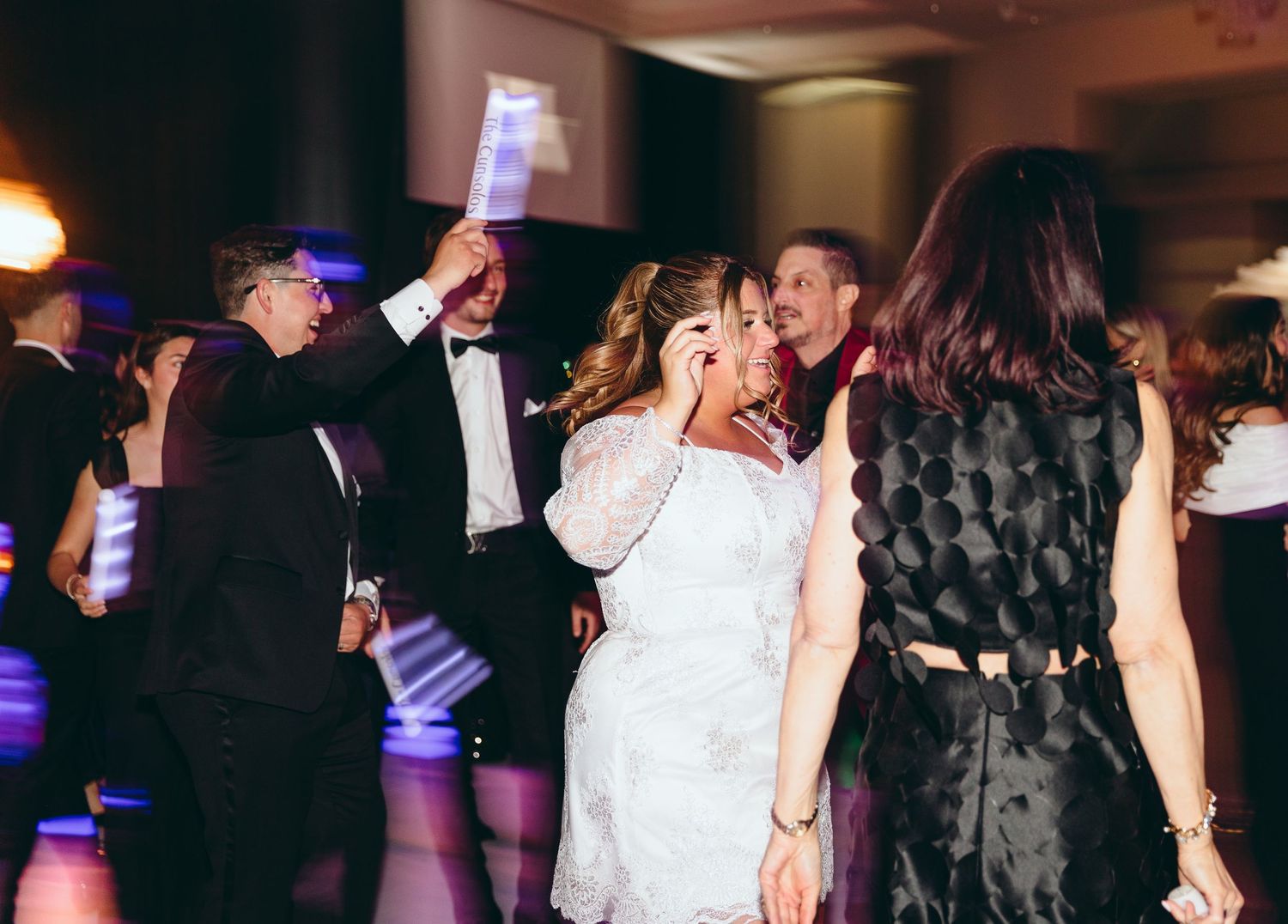 Wedding reception dance floor scene with guests celebrating and dancing.