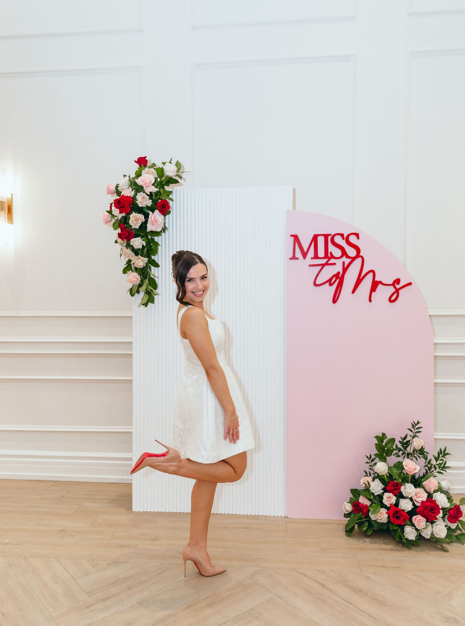 Bridal photo session setup with pink backdrop and floral arrangements.