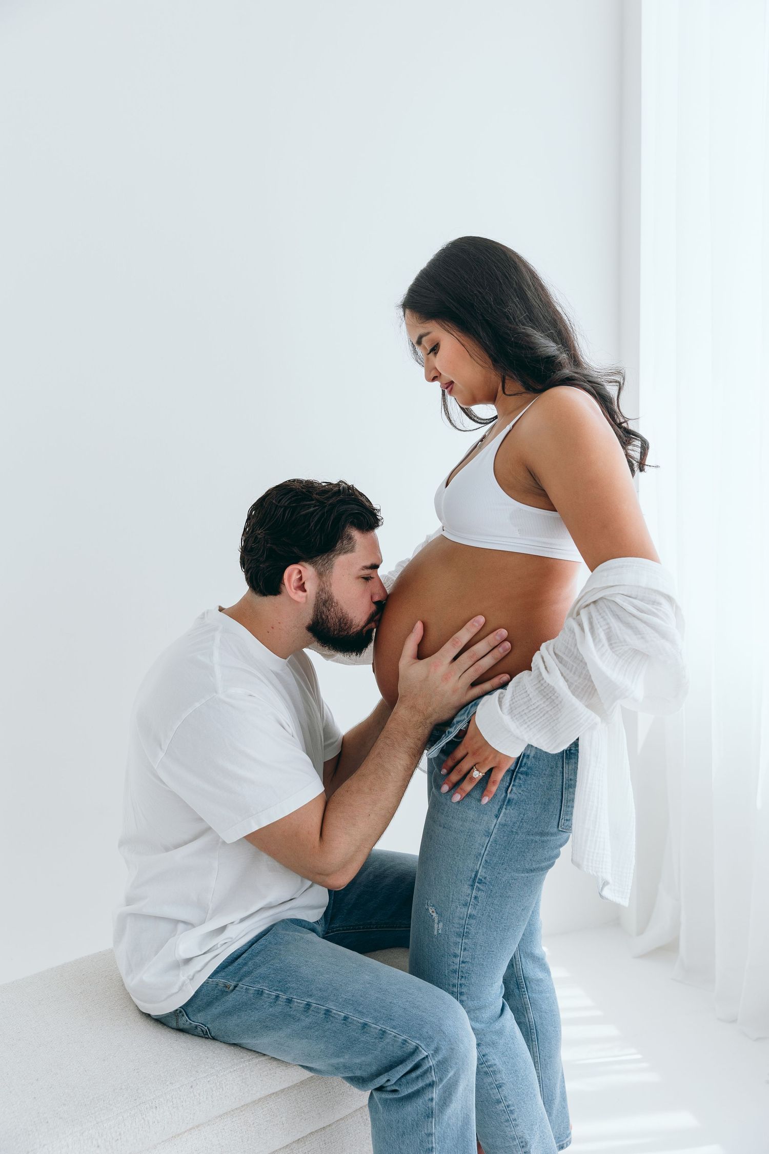 Intimate maternity photo session in an all-white studio setting.