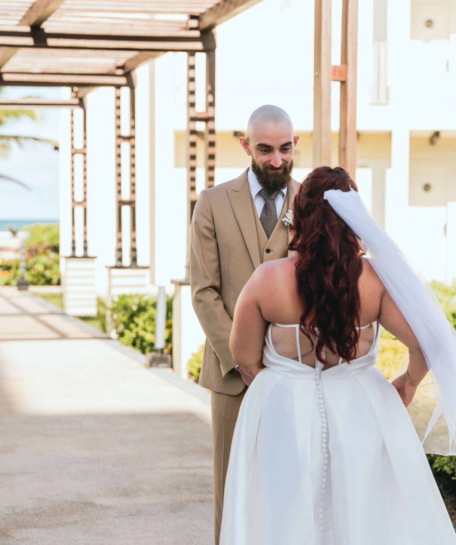 First look wedding moment captured under a covered walkway with natural lighting.