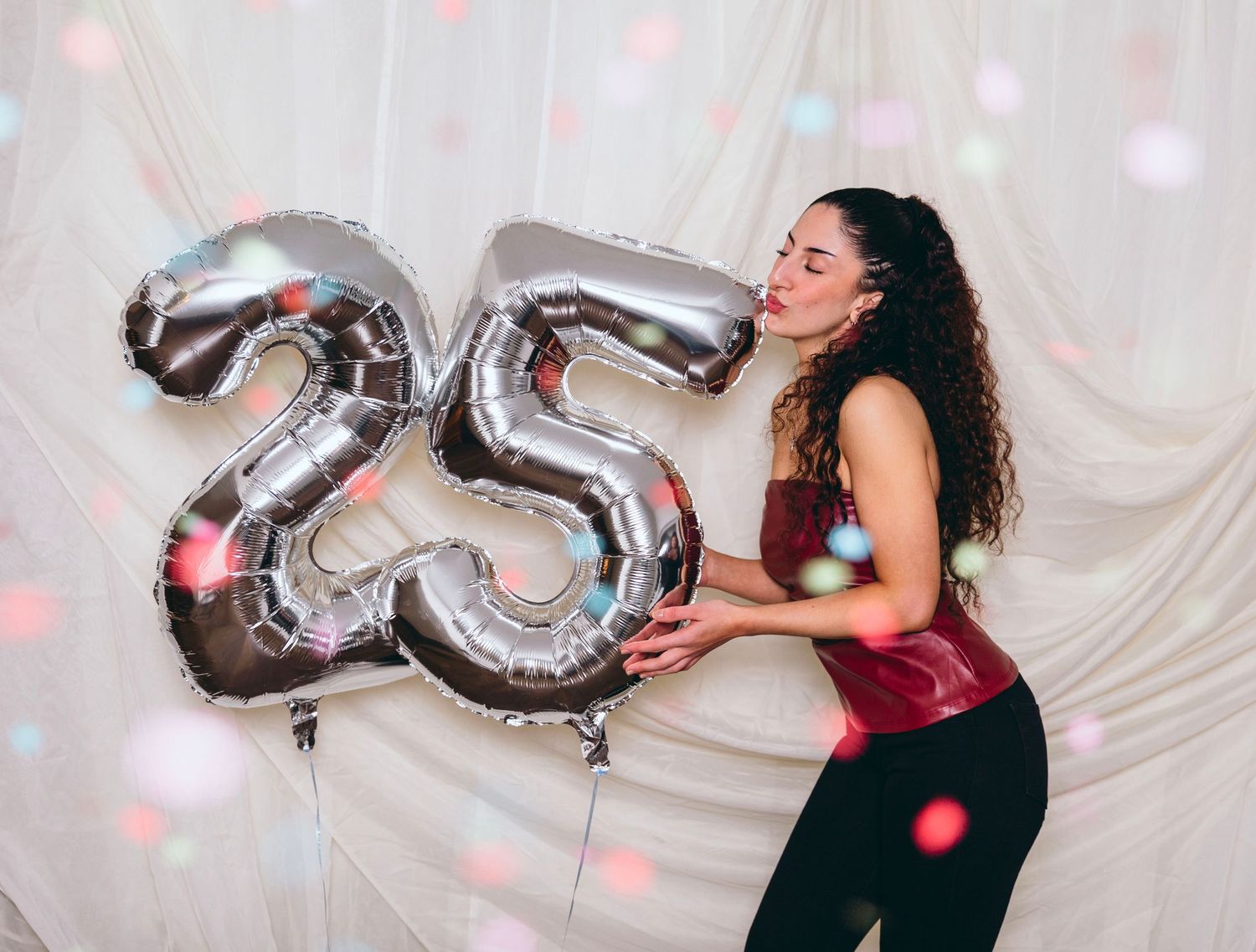 Silver number balloons and colorful confetti create a festive celebration atmosphere.